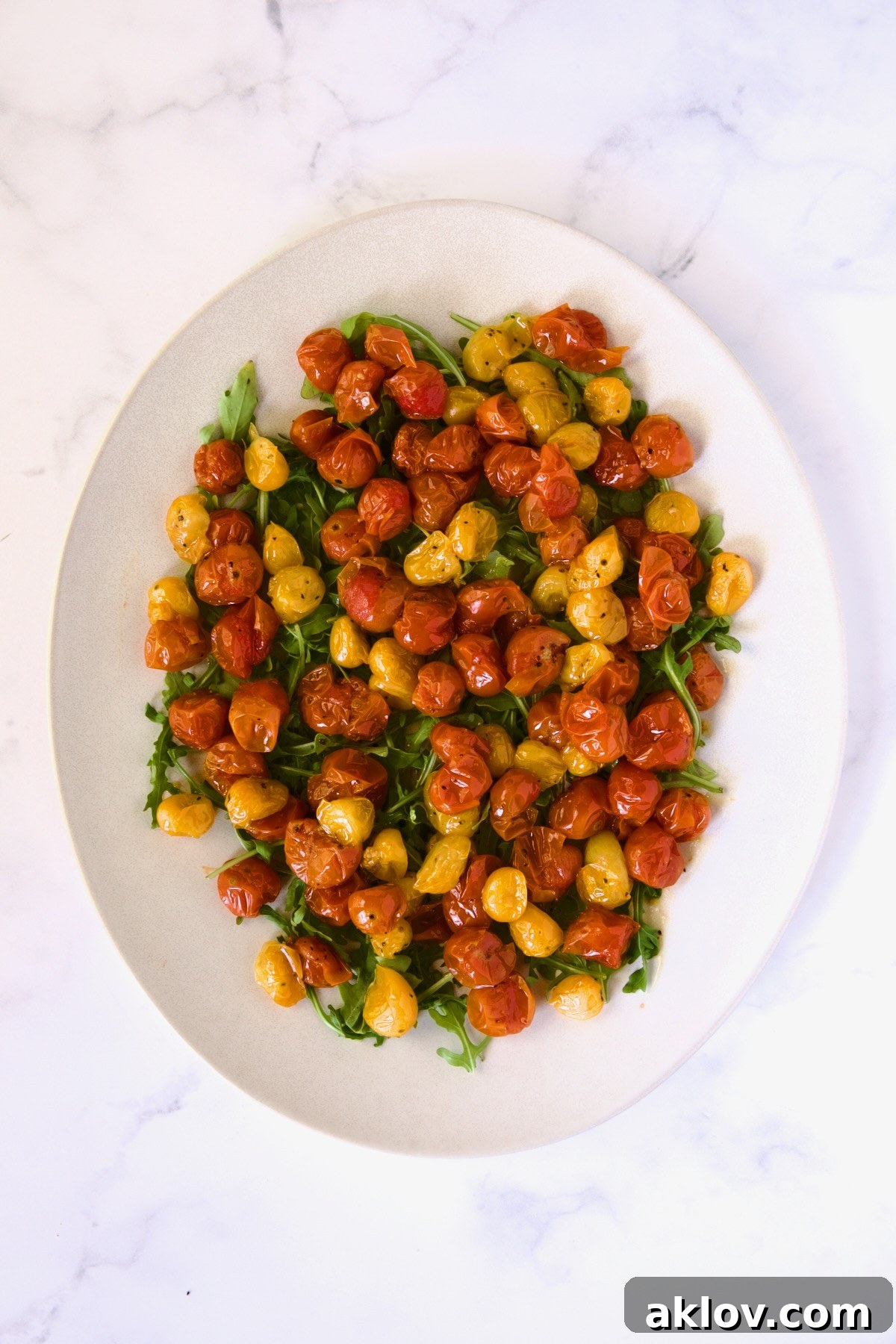 Creamy Burrata Caprese with Sweet Roasted Cherry Tomatoes 9 Roasted cherry tomatoes, including their juices, carefully arranged atop the bed of arugula on a white oval platter.
