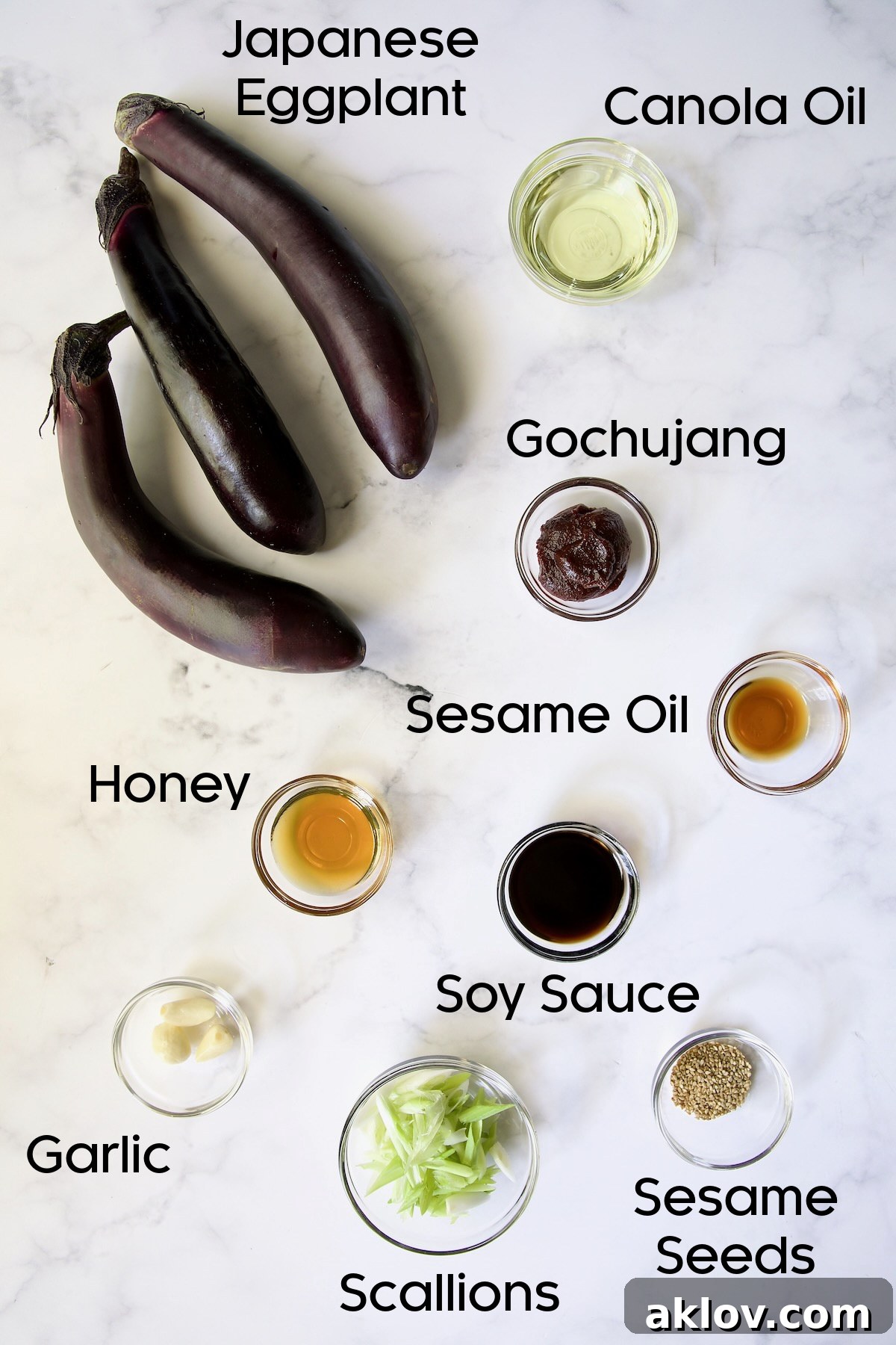 Ingredients for Gochujang Eggplant in glass bowls on marble surface.