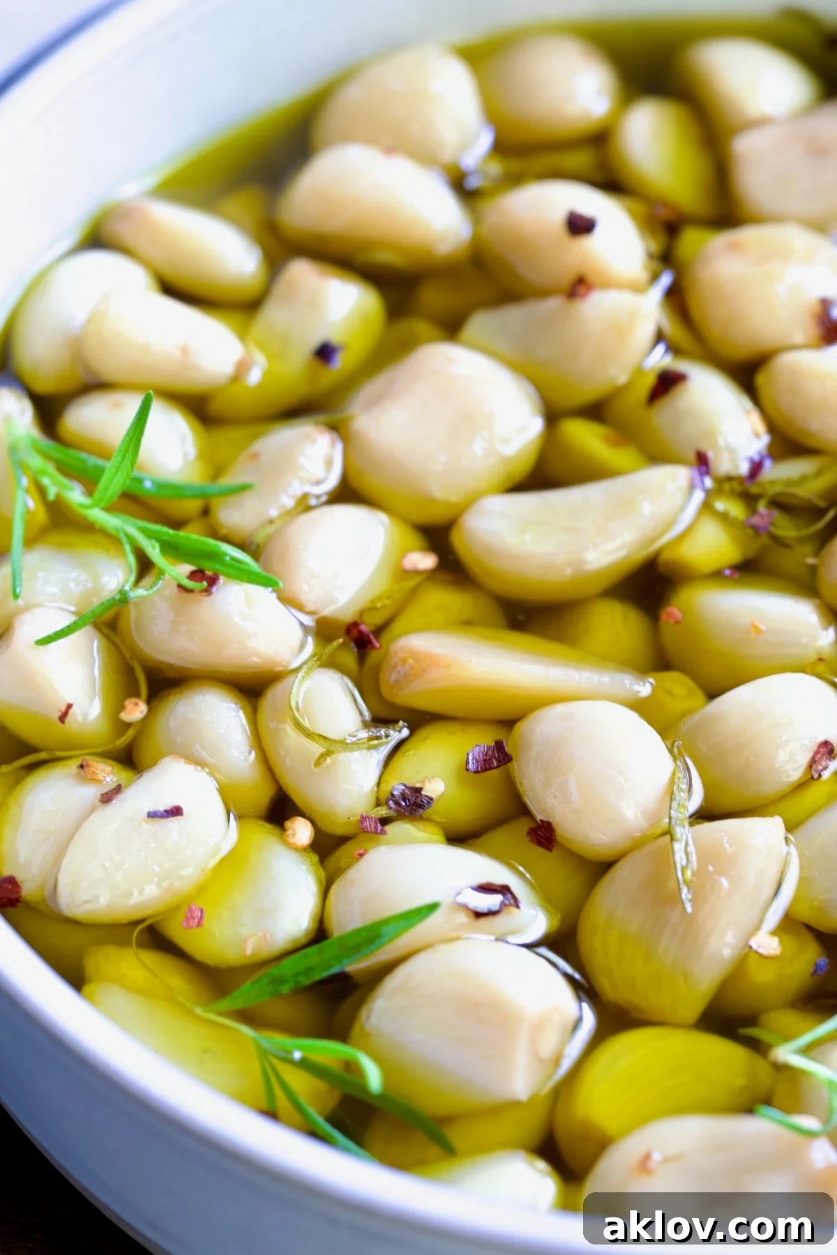 Garlic confit cloves resting in a round earthenware bowl, bathed in golden infused olive oil.