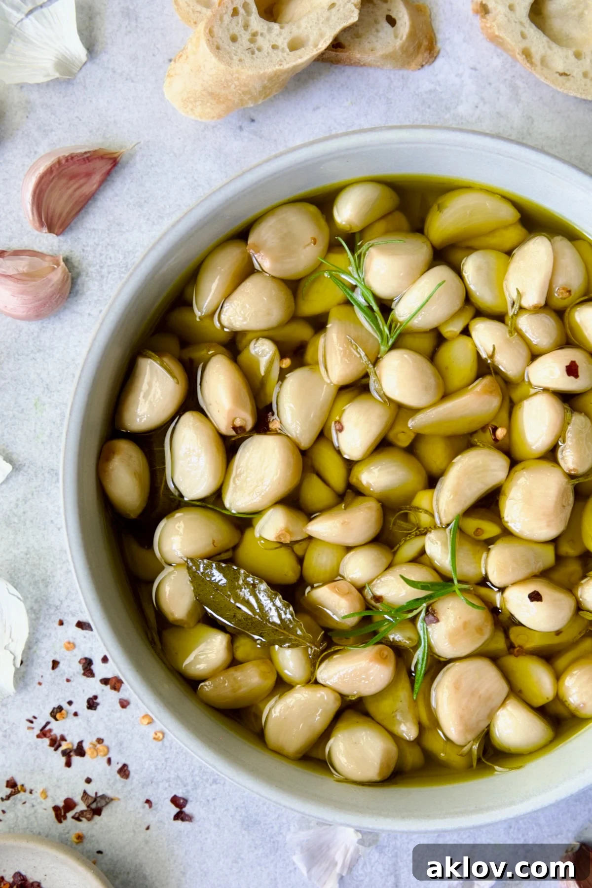 A close-up of garlic confit in an earthenware bowl, showing the tender cloves and rich olive oil.