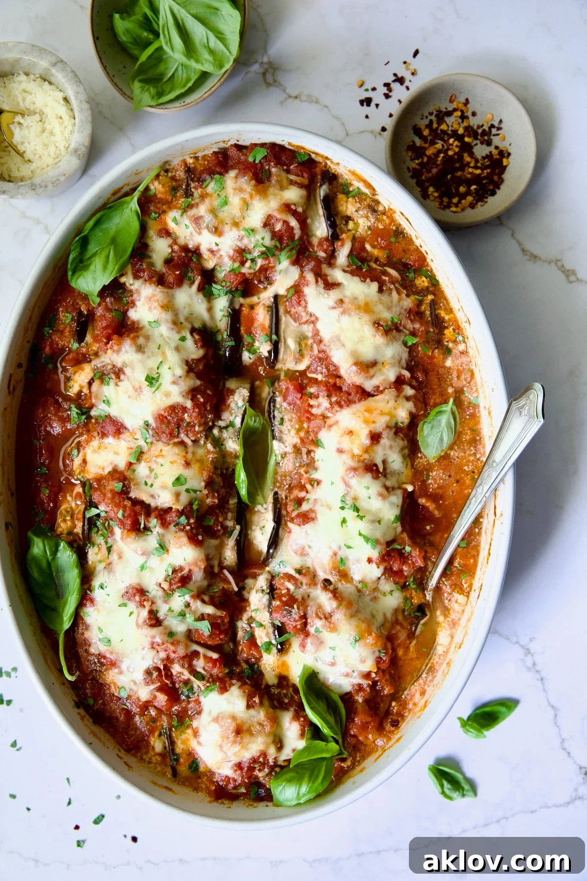 Four-Cheese Eggplant Rollatini in oval baking dish garnished with fresh basil.