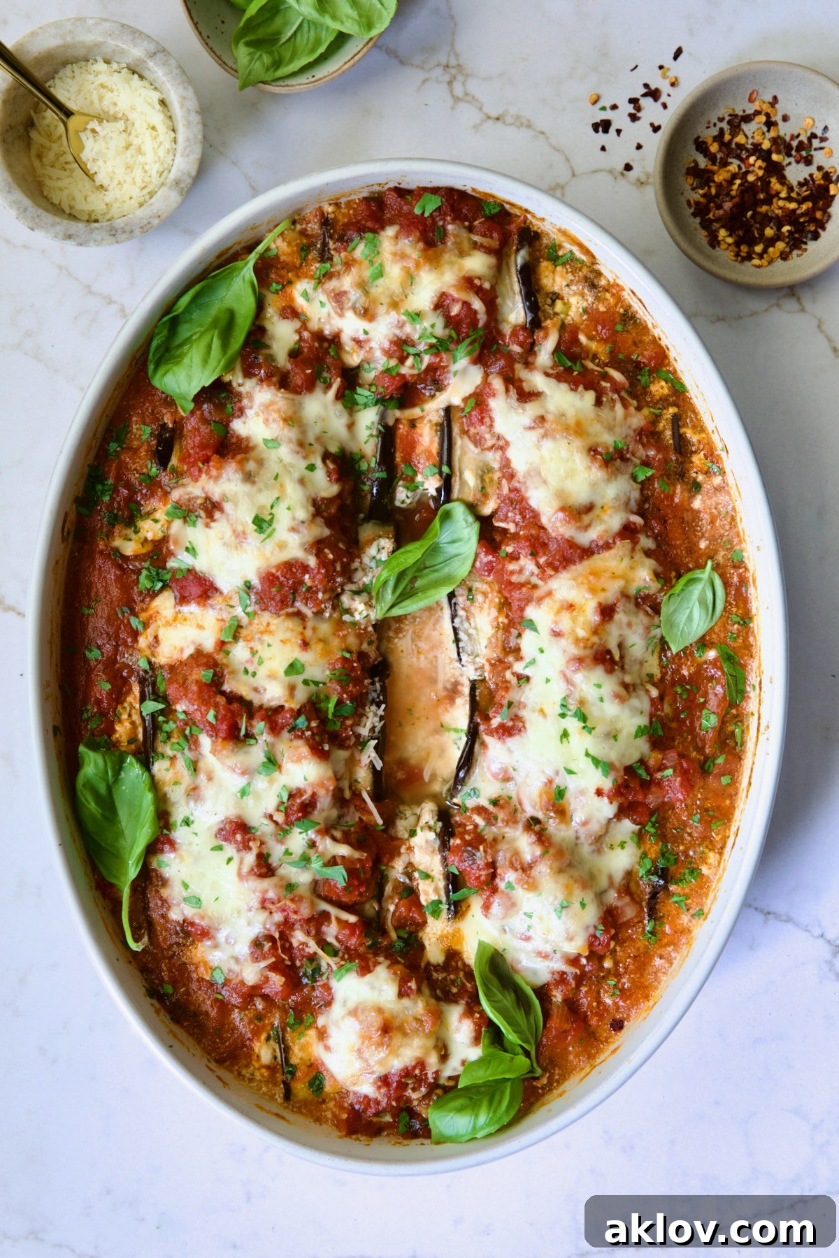 Baked Four-Cheese Eggplant Rollatini garnished with fresh basil.