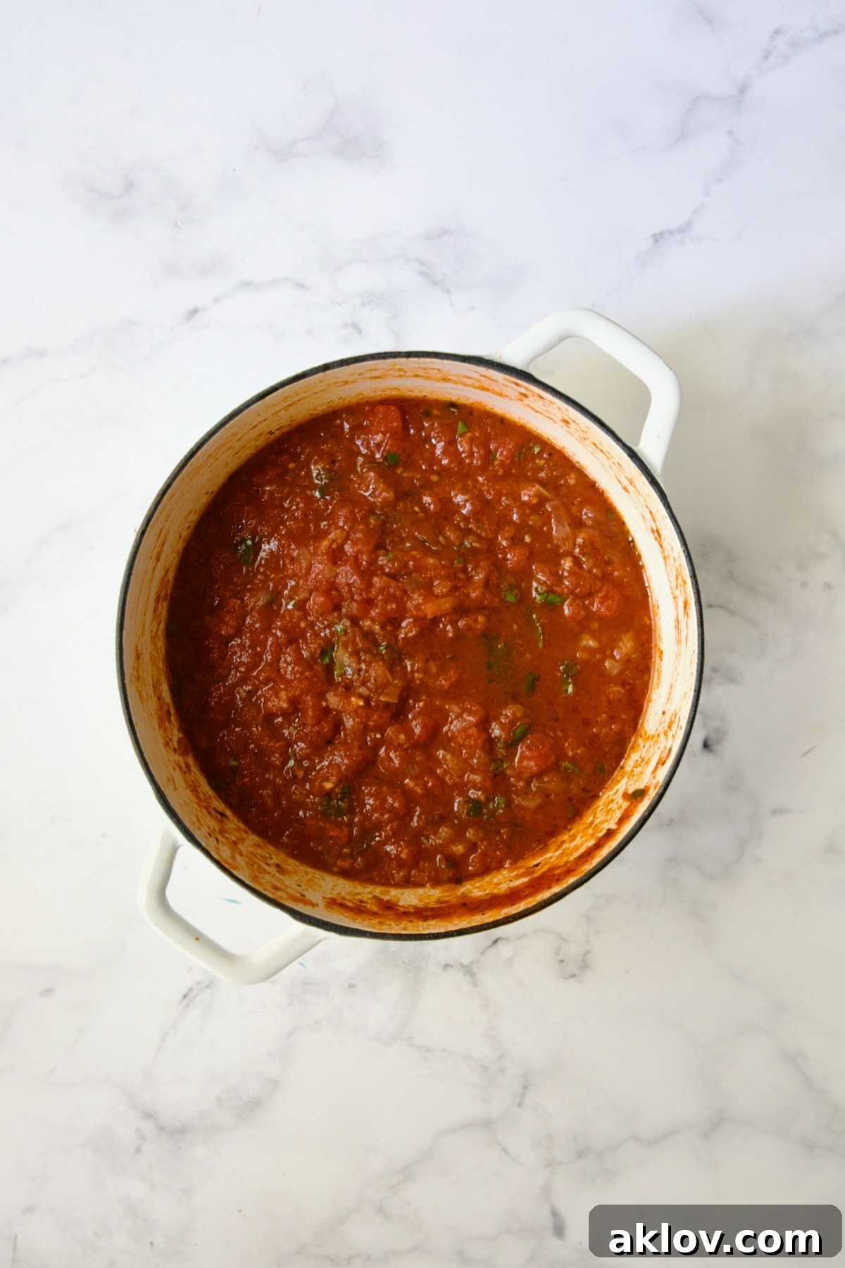 Cooked tomato sauce in white Dutch oven.