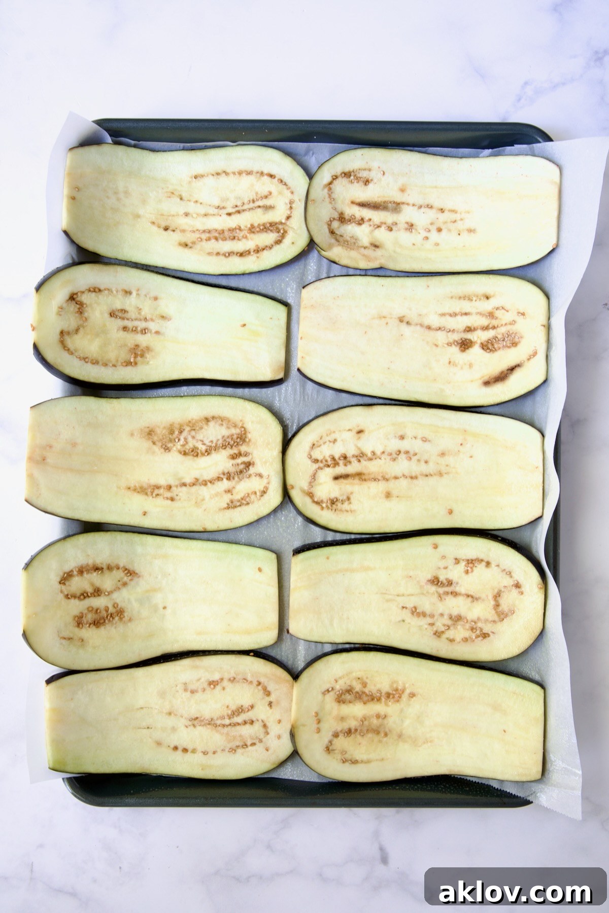Ten eggplant slices on parchment paper-lined baking sheet.