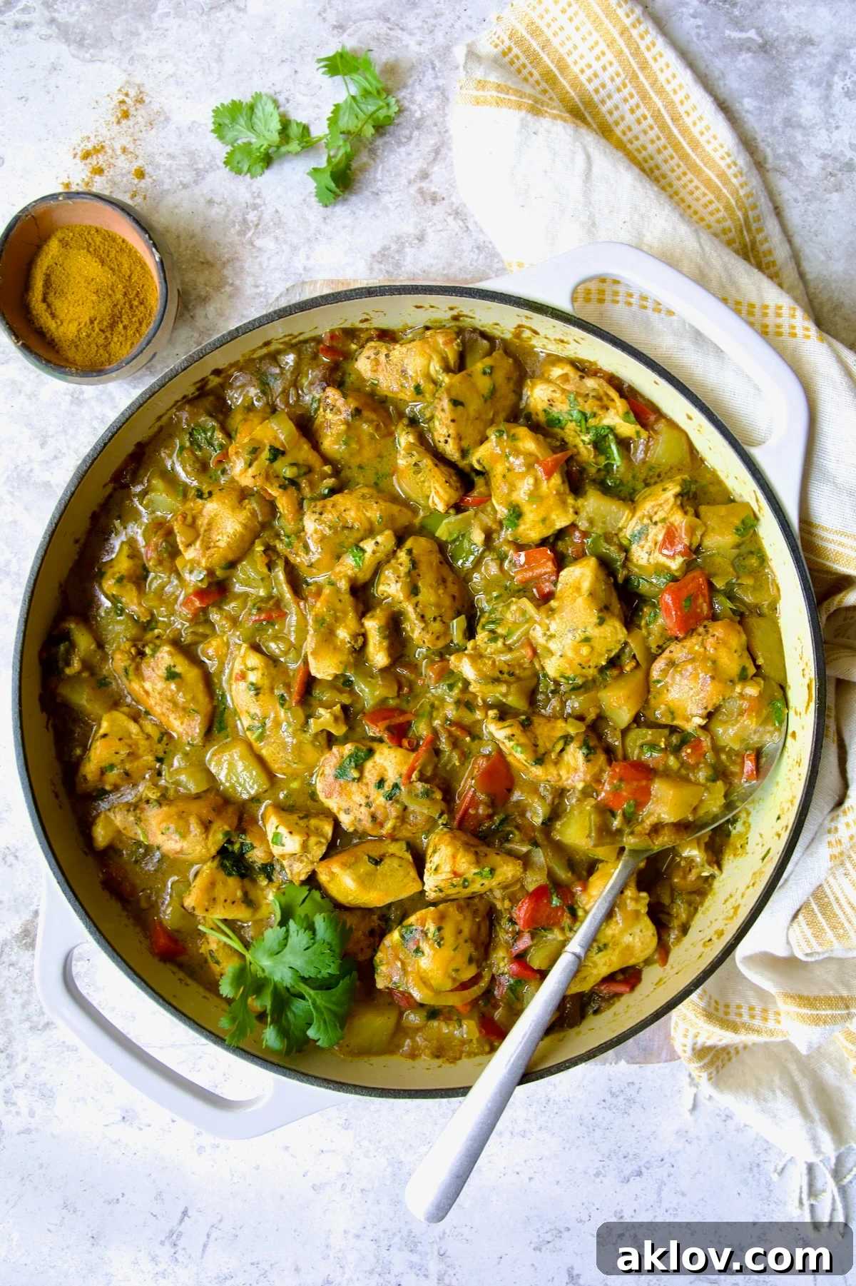 Comforting Chicken Potato Curry 2 A vibrant Chicken and Potato Curry in a white enamel cast iron skillet, garnished with fresh cilantro, ready to be served.