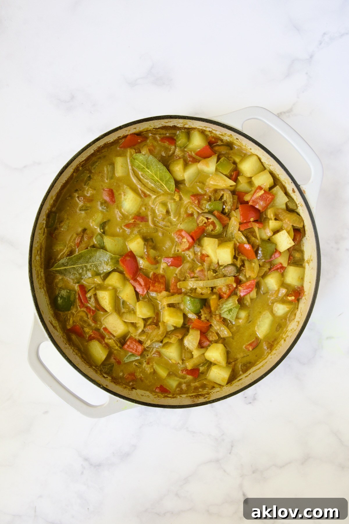 Cooked potatoes, peppers and onions in white enamel cast iron skillet.