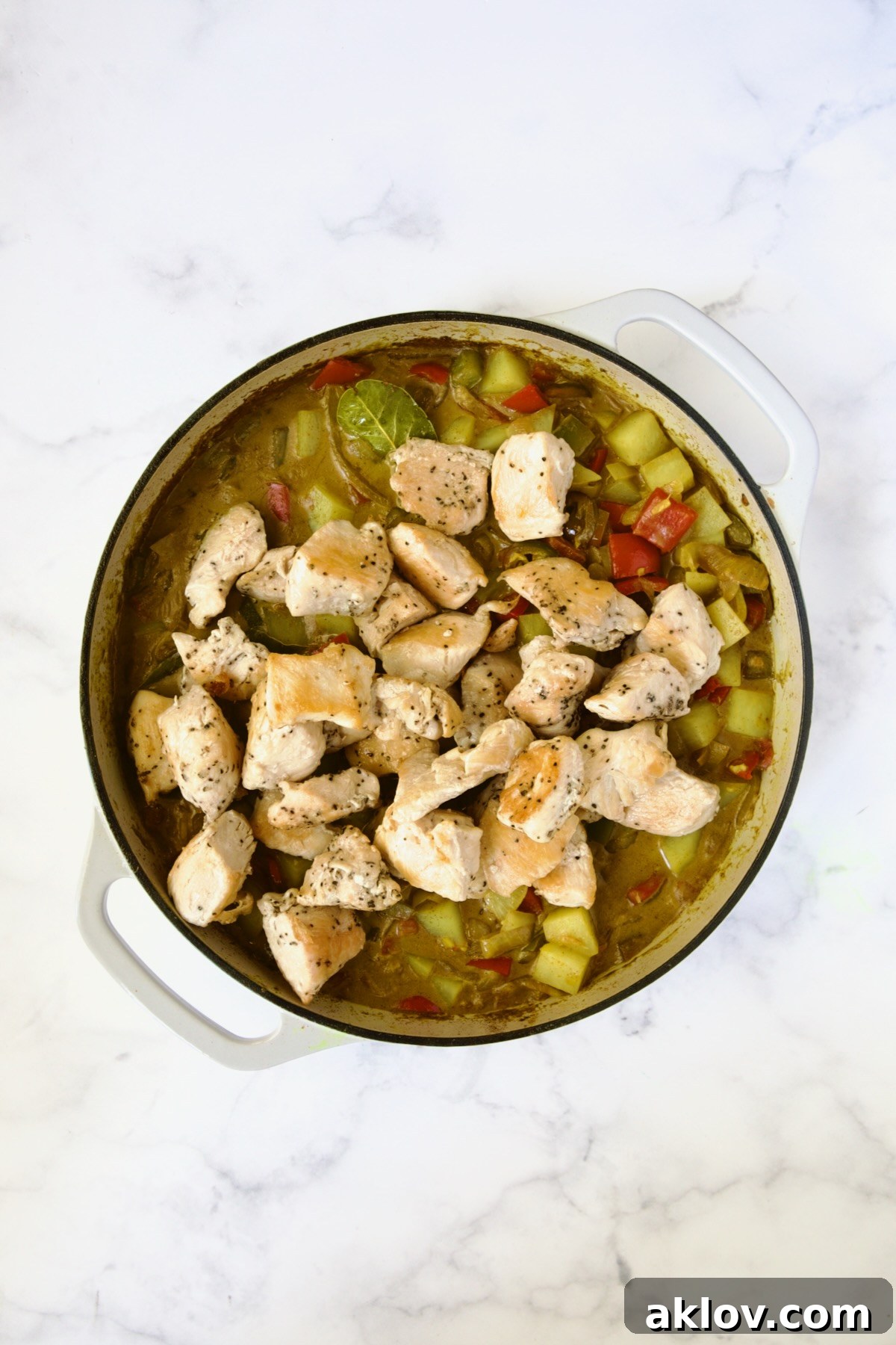 Chicken added back to curry in white enamel cast iron skillet.