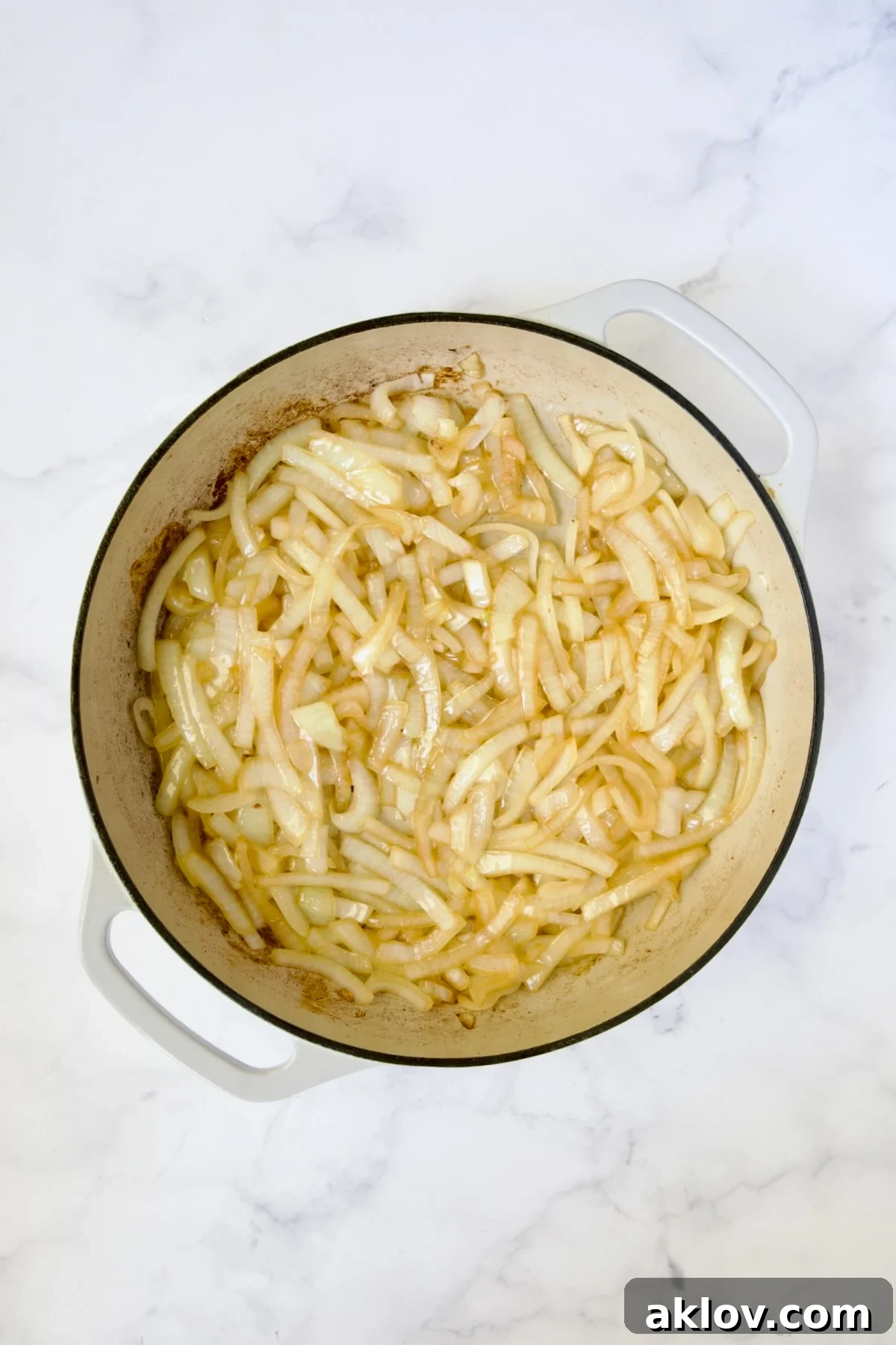 Lightly cooked onions in white enamel cast iron skillet.