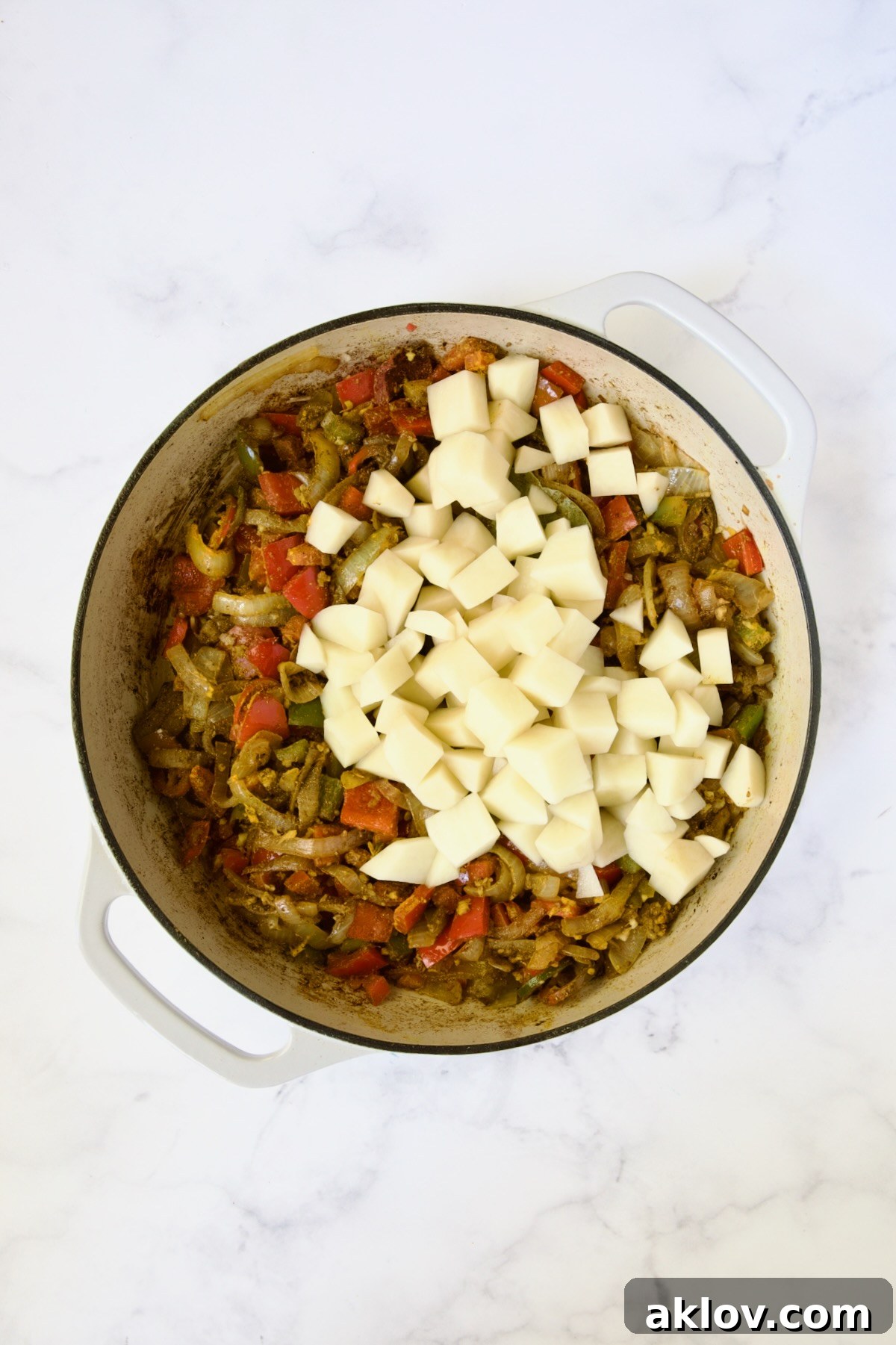 Potatoes added to onions, peppers and spices but not yet cooked.