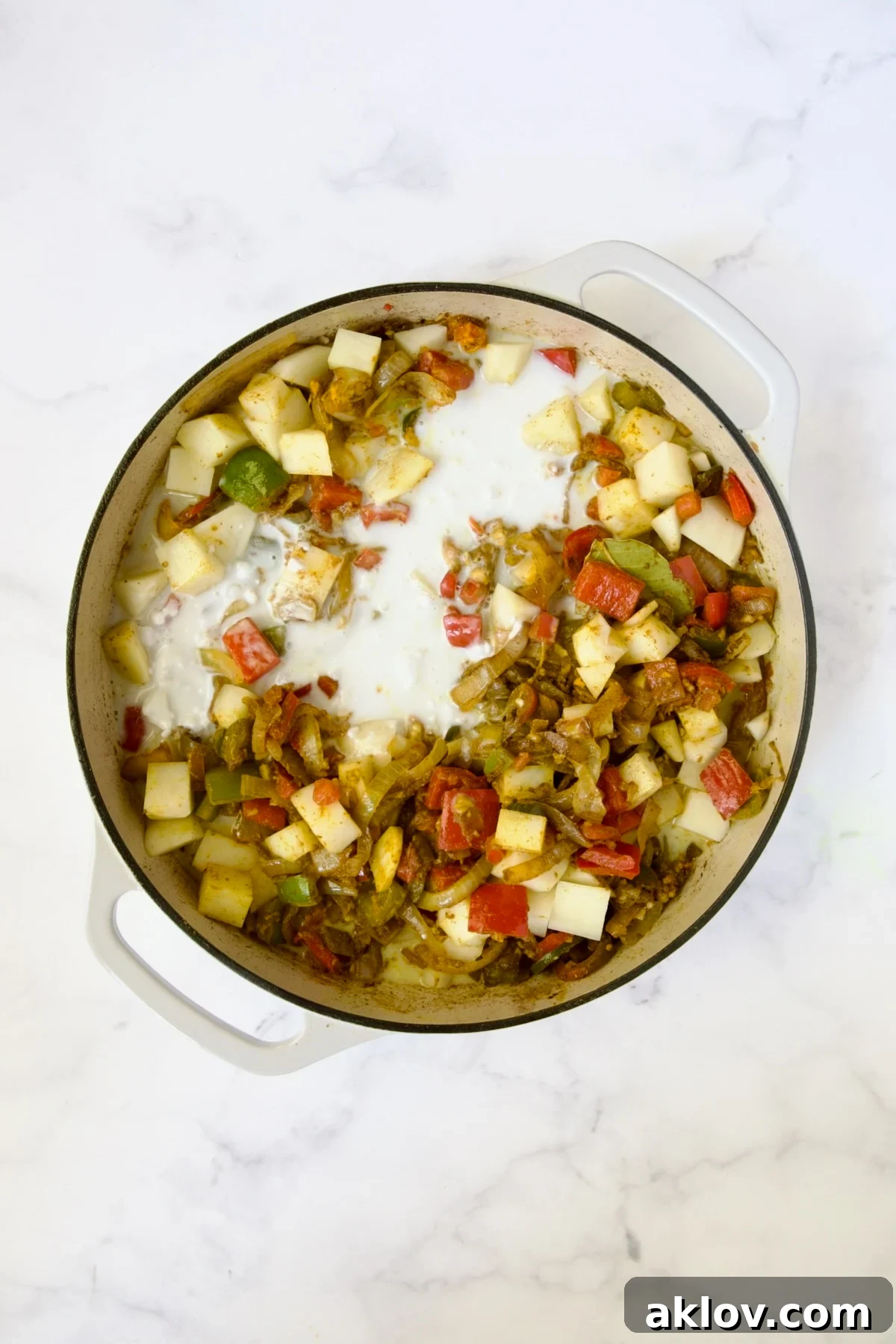 Comforting Chicken Potato Curry 10 Creamy coconut milk enriching the cooked vegetables and potatoes, ready to simmer into a luscious curry sauce.