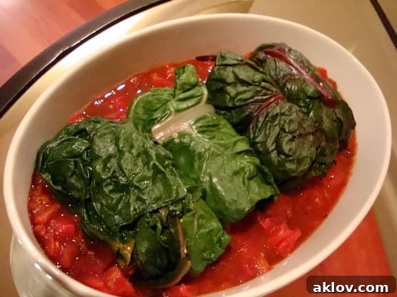 Photo of stuffed Swiss chard rolls on tomato sauce.