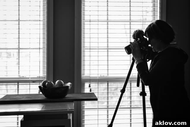 Photo of Carol Borchardt taking a food photo in front of window.