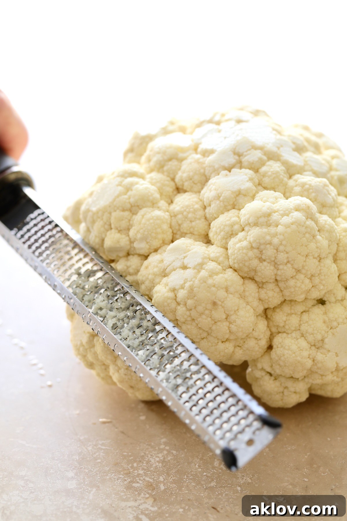 Microplane grating brown spots off head of cauliflower.