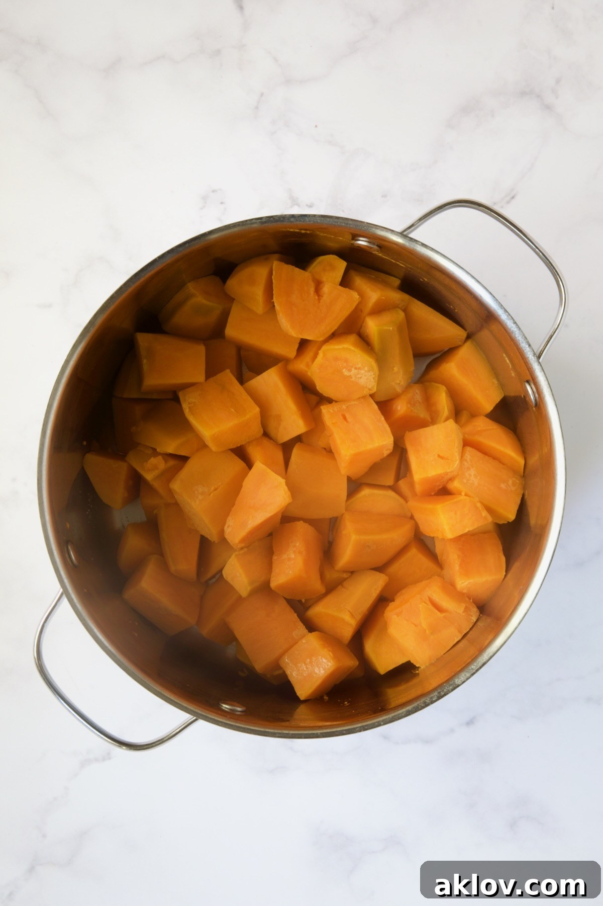 Cooked sweet potatoes, perfectly tender, in a stainless steel pot after boiling.