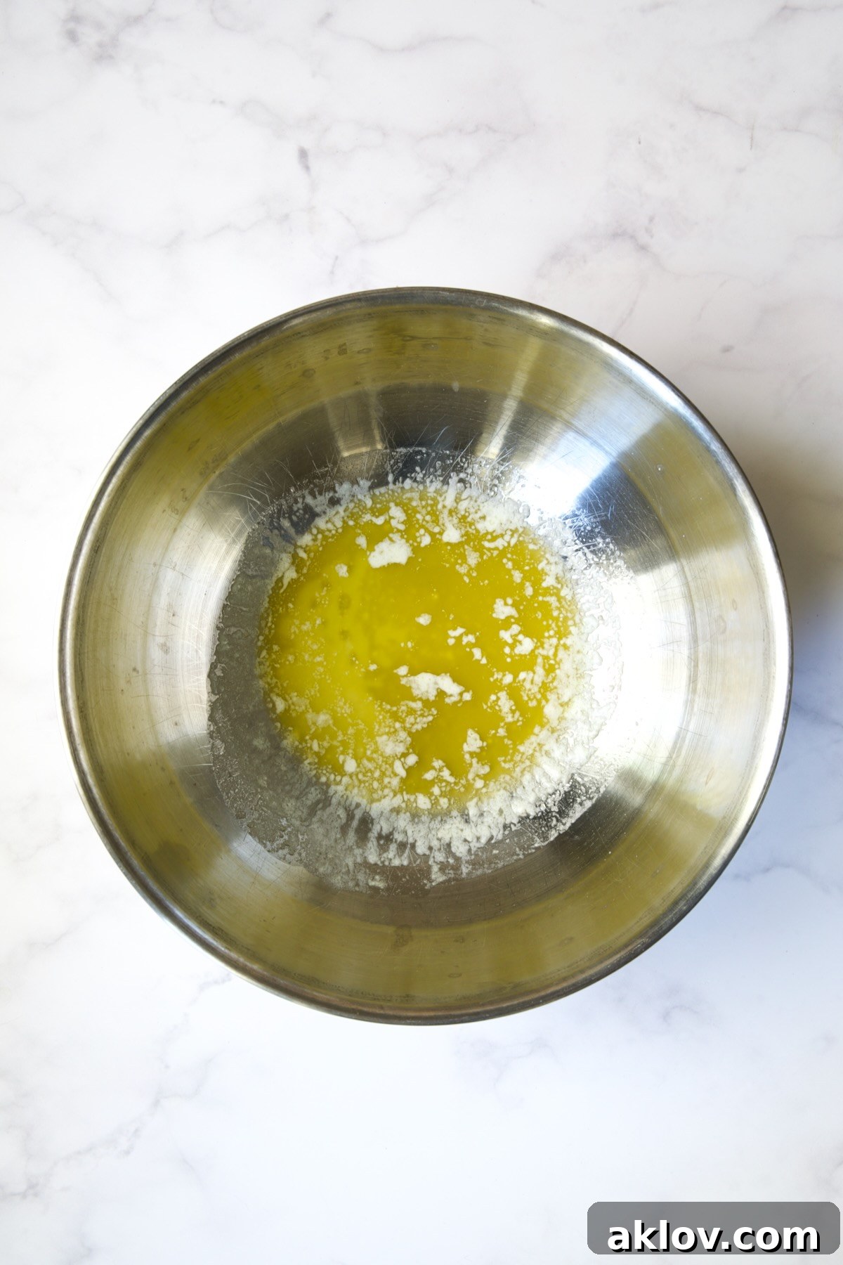 Melted butter in a gleaming stainless steel bowl, ready for the sweet potatoes.