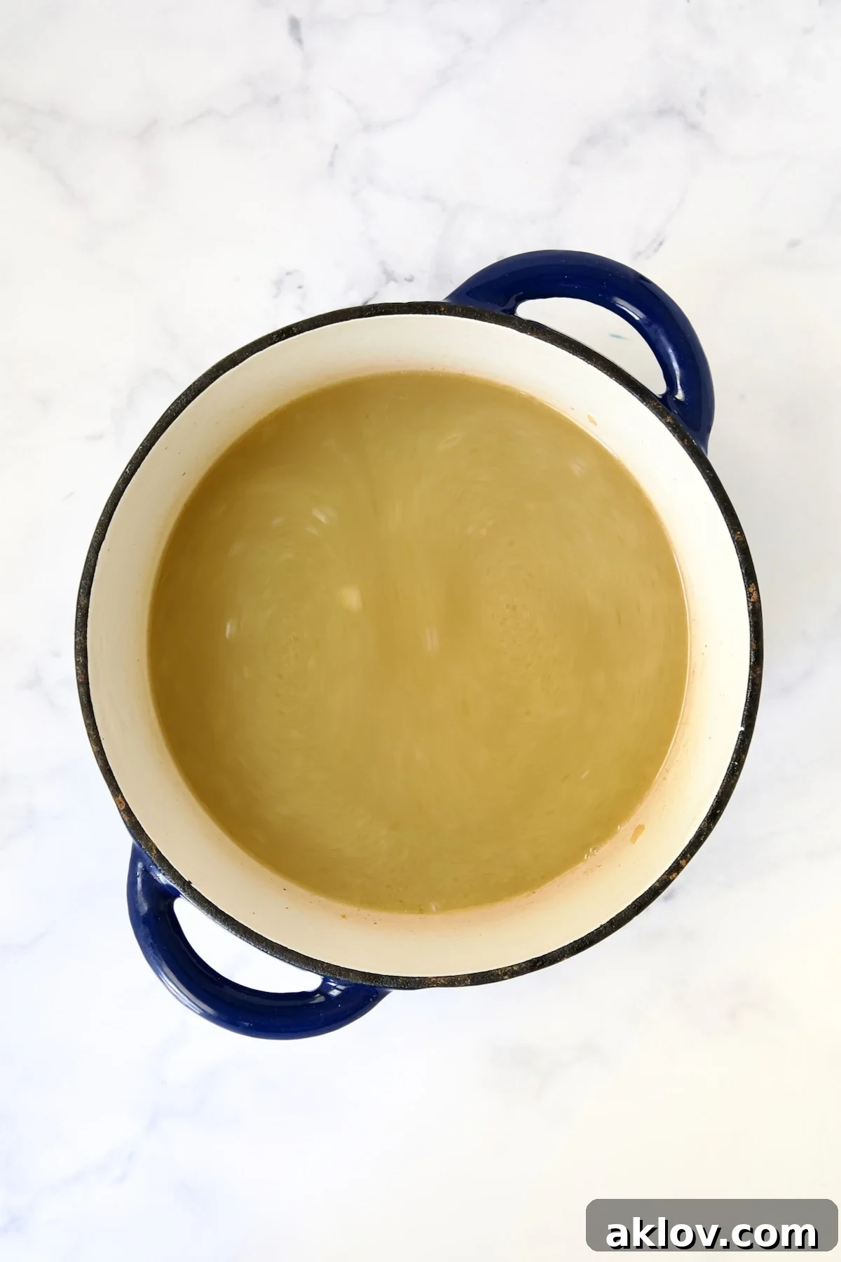 Chicken broth added to blue Dutch oven.