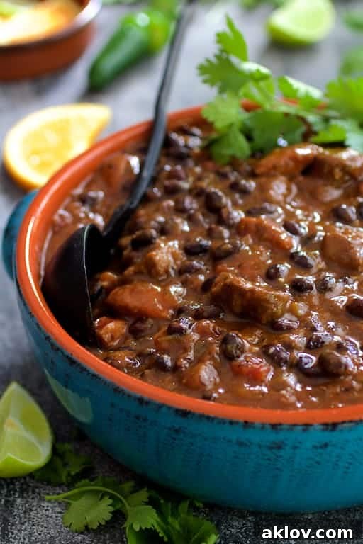 A large blue serving bowl filled with un-garnished Feijoada (Brazilian Beef Stew), showcasing the rich, dark stew before the final fresh toppings are added.