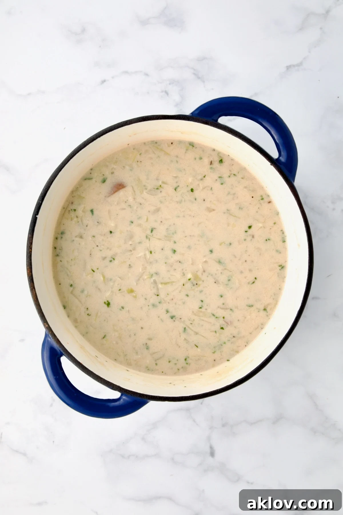 The thickened half-and-half and flour combination expertly blended into the soup in a blue cast iron Dutch oven.