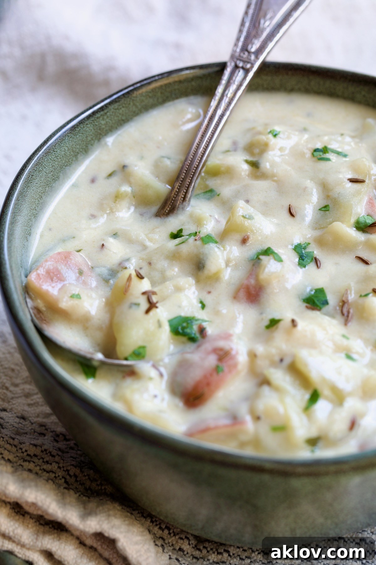 A single bowl of Creamy Cabbage and Potato Soup in a vibrant green bowl, accompanied by a soup spoon, enticingly presented.