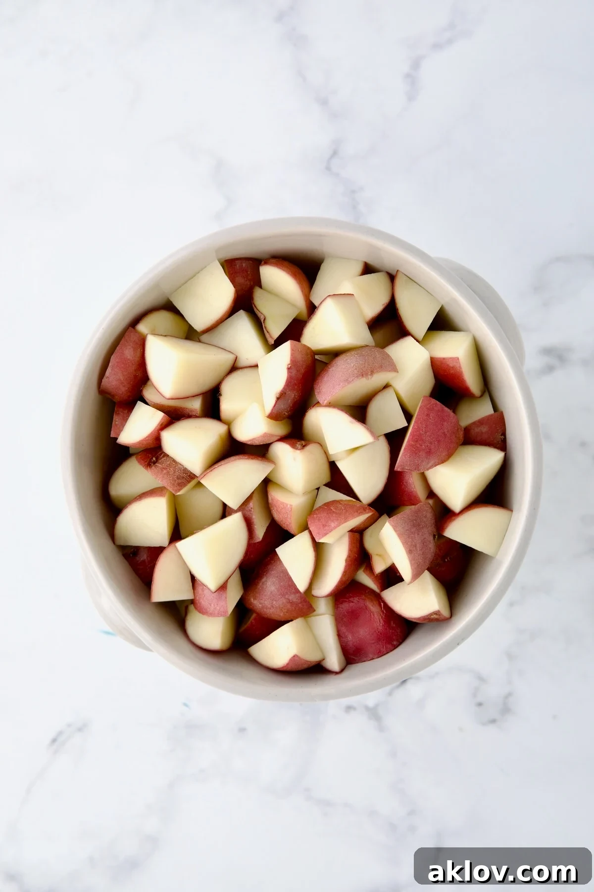 A colander filled with freshly quartered red potatoes, ready for dicing.