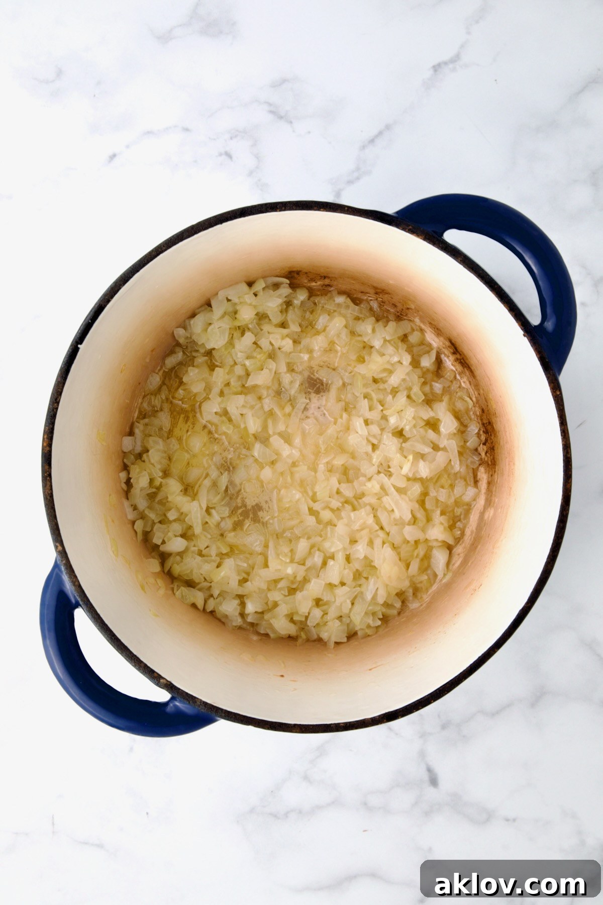 Sautéed onions achieving perfect tenderness in a blue cast iron Dutch oven.