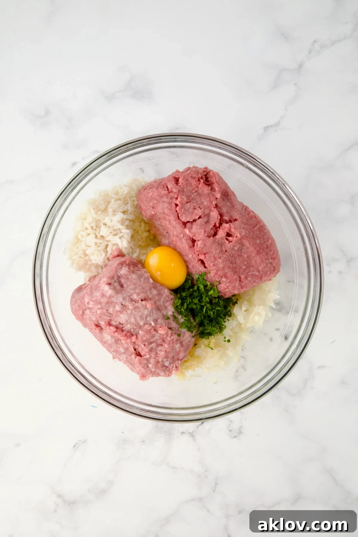 Filling for Polish Stuffed Cabbage rolls in glass bowl consisting of cooked rice, meats, egg, parsley and onion.