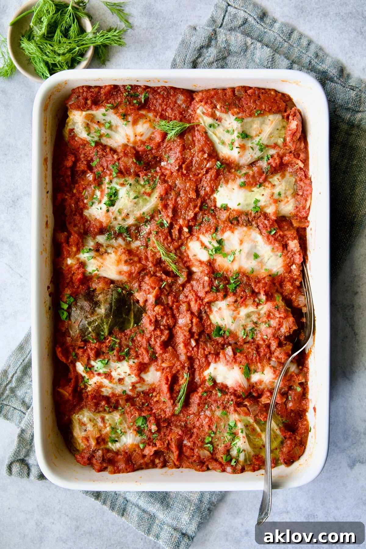 Baking dish full of Polish Stuffed Cabbage on blue napkin after being baked.