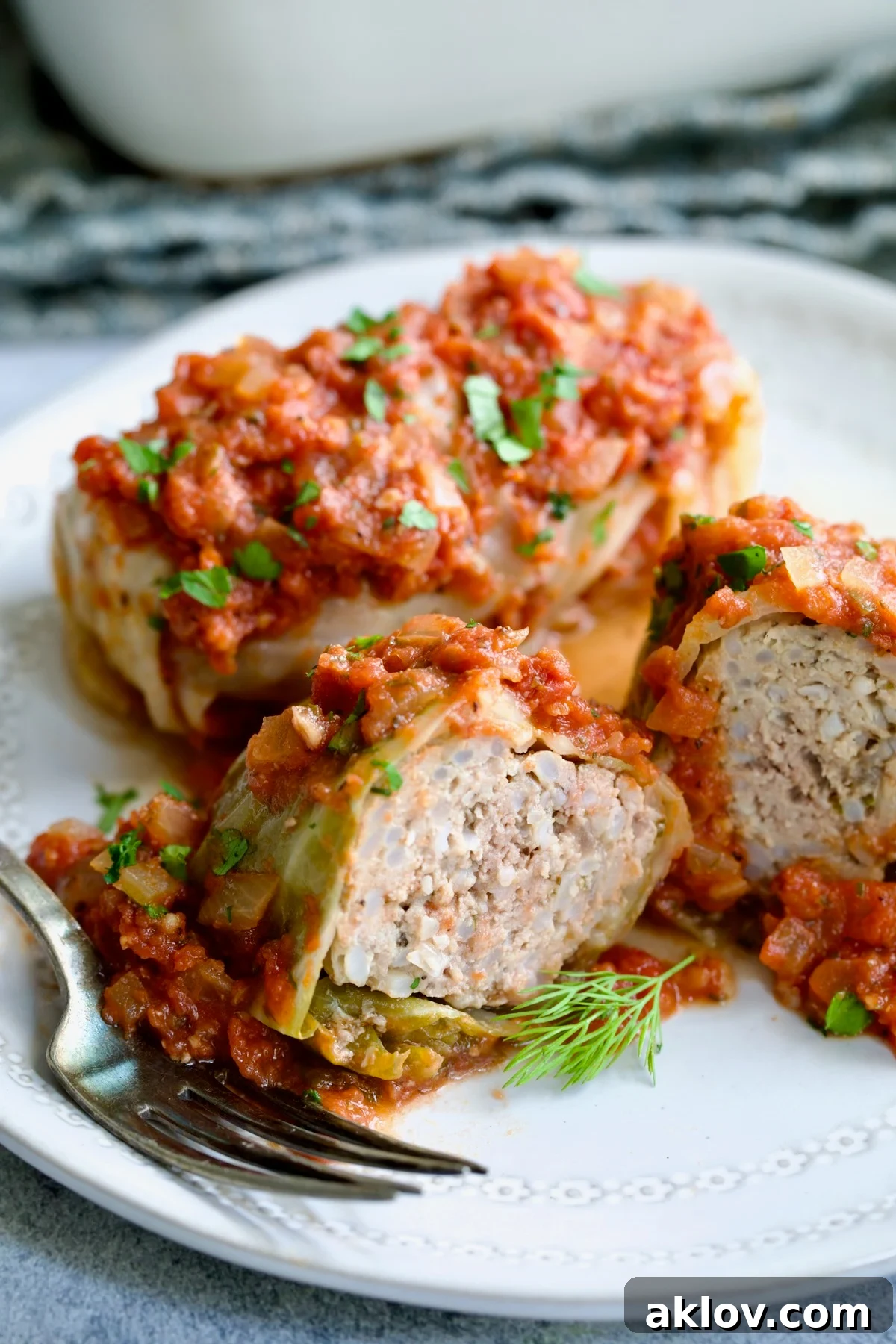 Polish Stuffed Cabbage roll cut in half to expose filling on white plate.