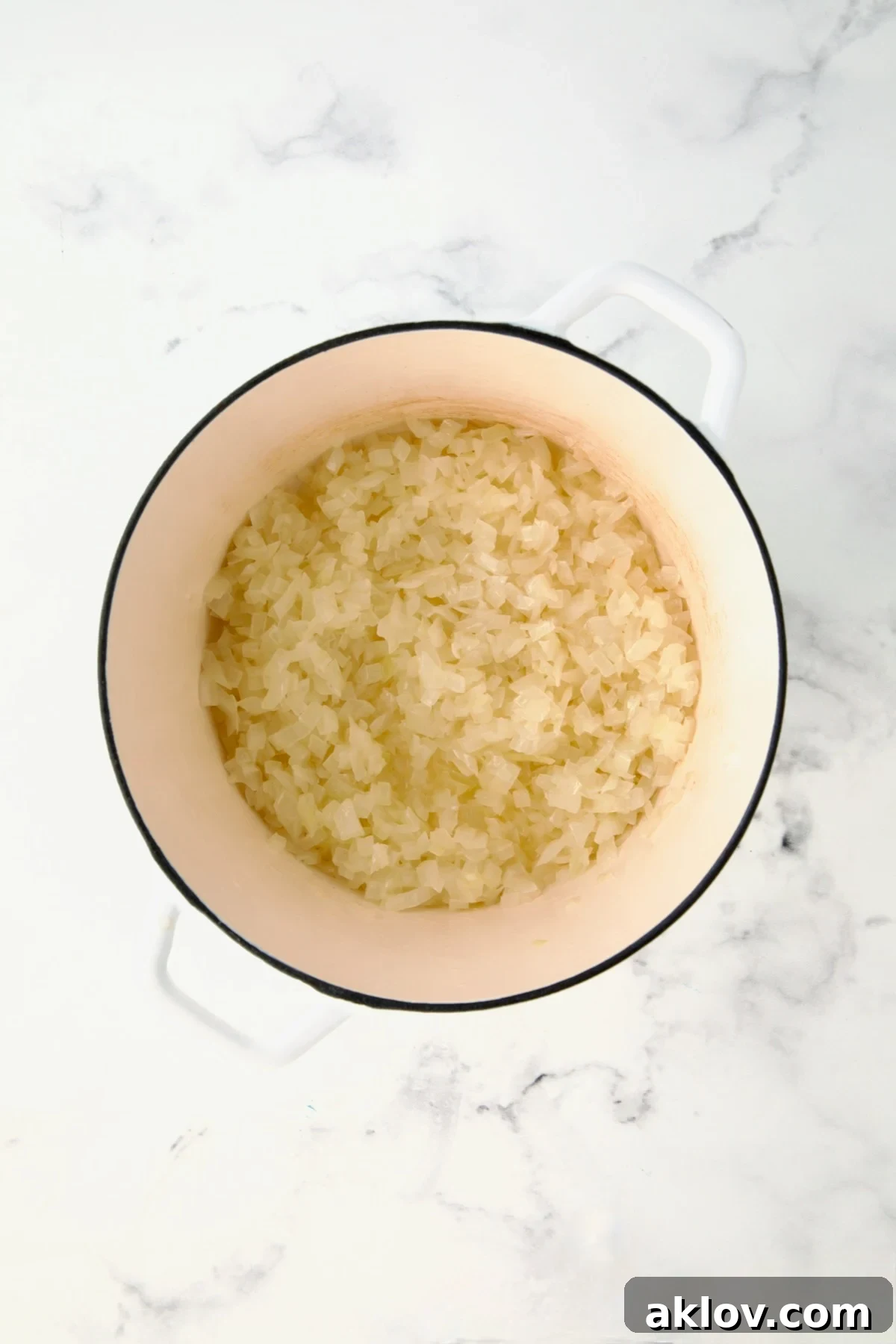 Partially cooked onions in white Dutch oven.
