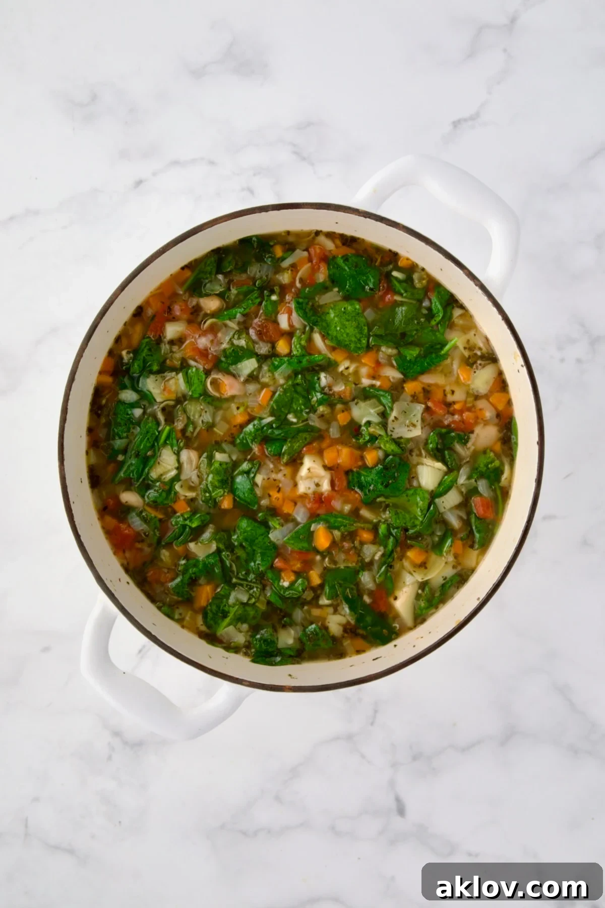 The finished Vegetable Bean Soup in a white Dutch oven, ready to be served.