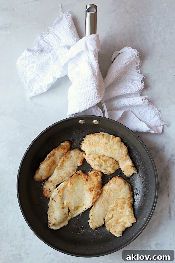 Overhead shot of turkey scallopini in large nonstick skillet that has been browned on both sides