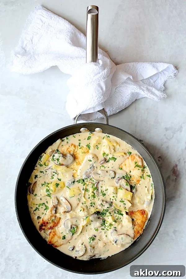 Turkey Scallopini in Sherry Cream Sauce with Mushrooms and Artichoke Hearts - Overhead shot of finished dish in skillet with white towel wrapped around handle
