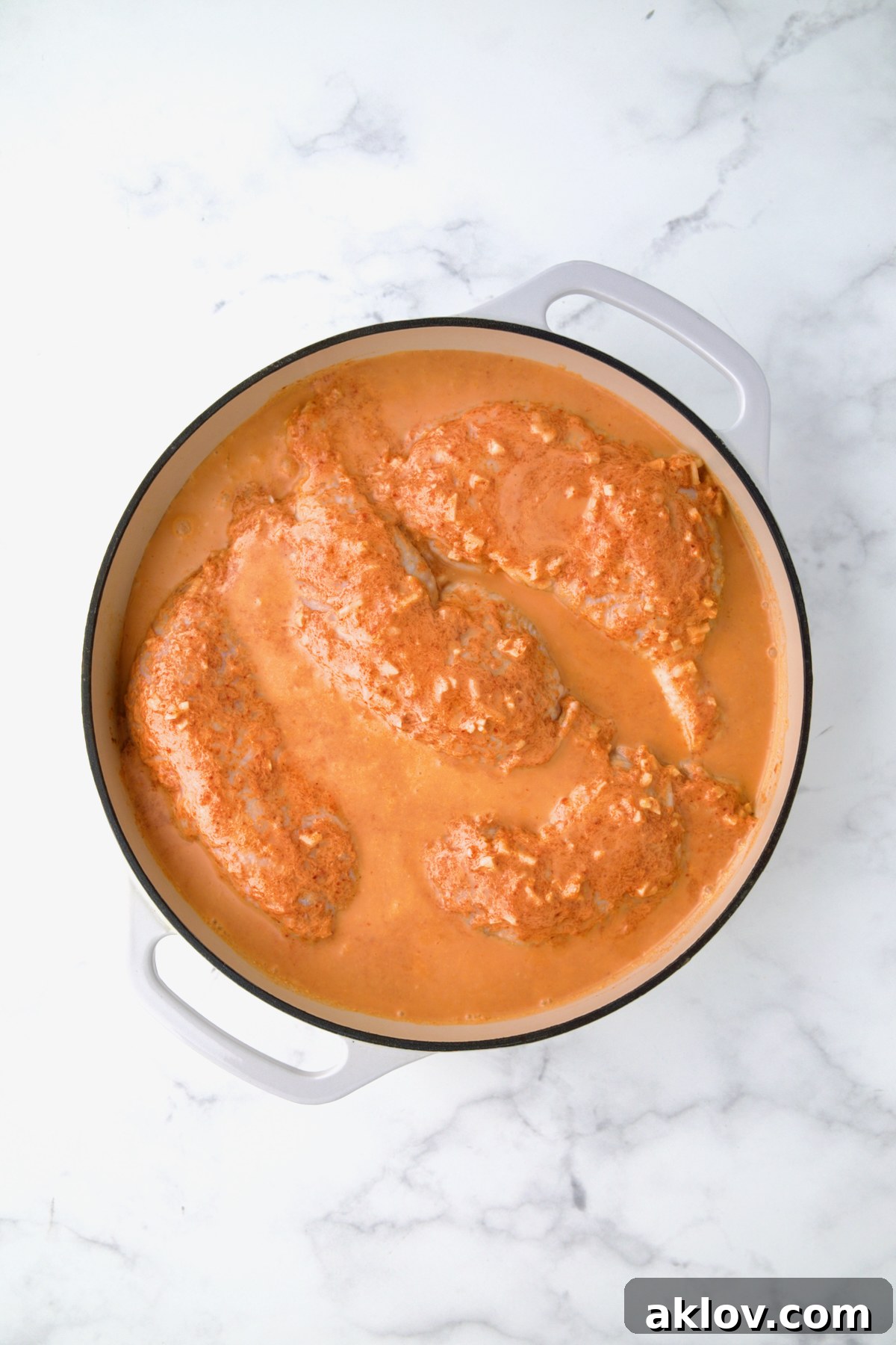 Spicy Thai Red Curry Chicken Drumsticks 6 Coconut milk combination poured over chicken legs in white enamel cast iron skillet.