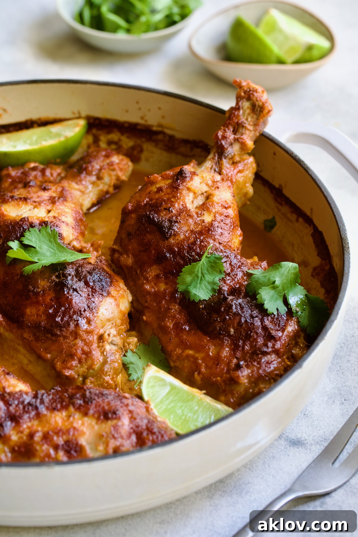 Spicy Thai Red Curry Chicken Drumsticks 9 Thai Red Curry Braised Chicken Legs in white enamel cast iron skillet garnished with cilantro and lime wedges.