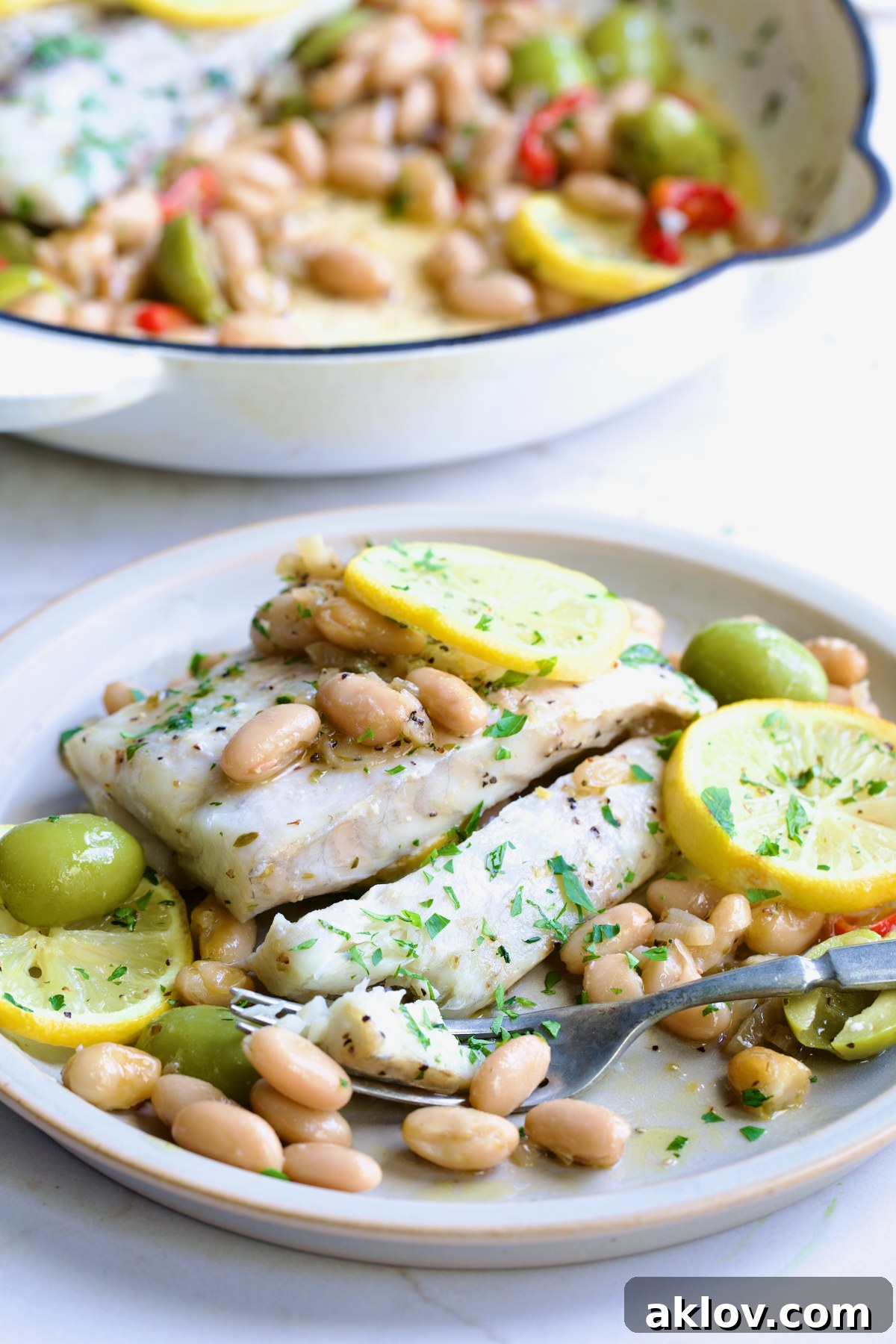 Serving of Mediterranean Fish and White Bean Skillet on round white plate.