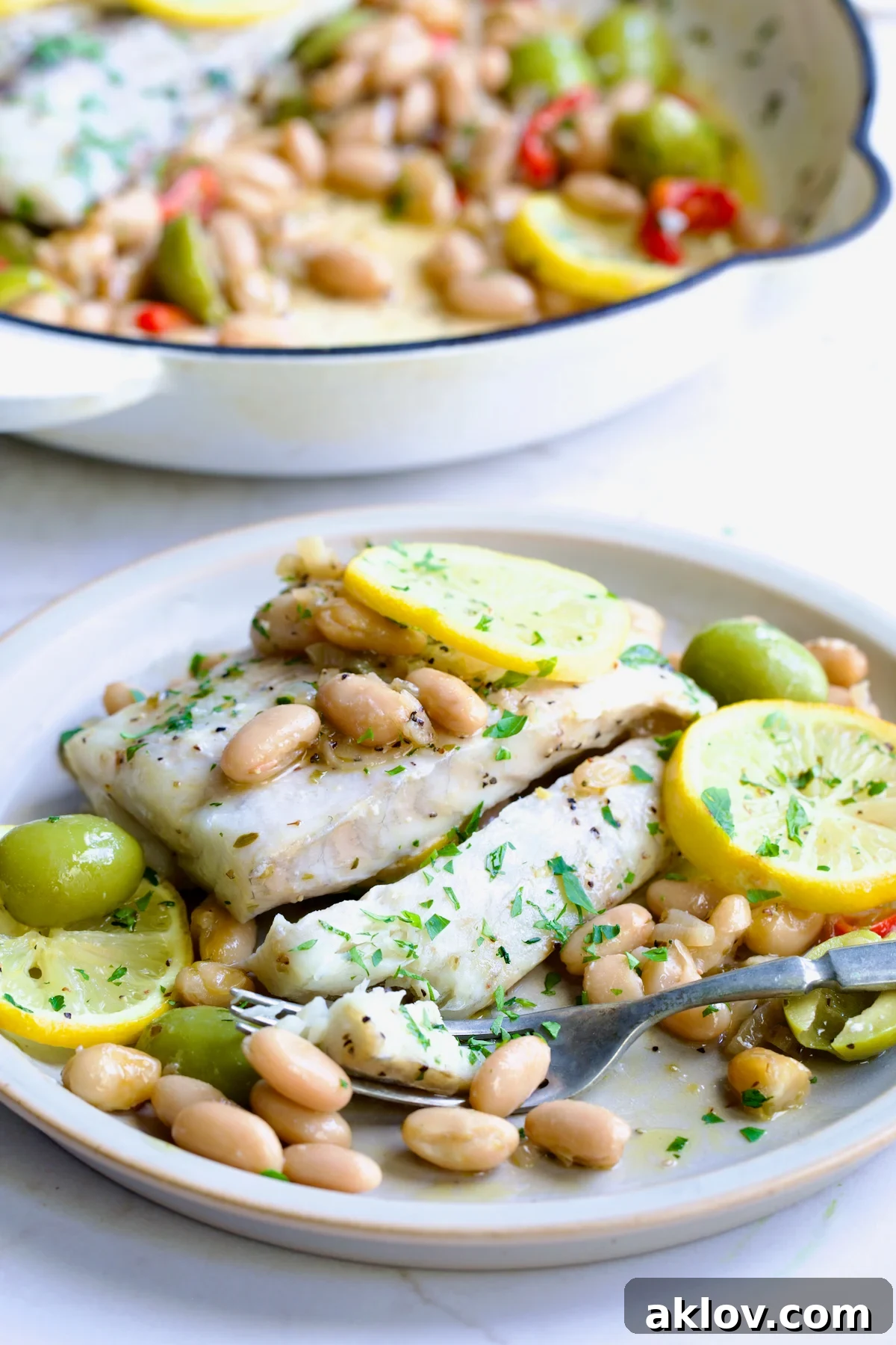 Serving of Mediterranean Fish and White Bean Skillet on round white plate.