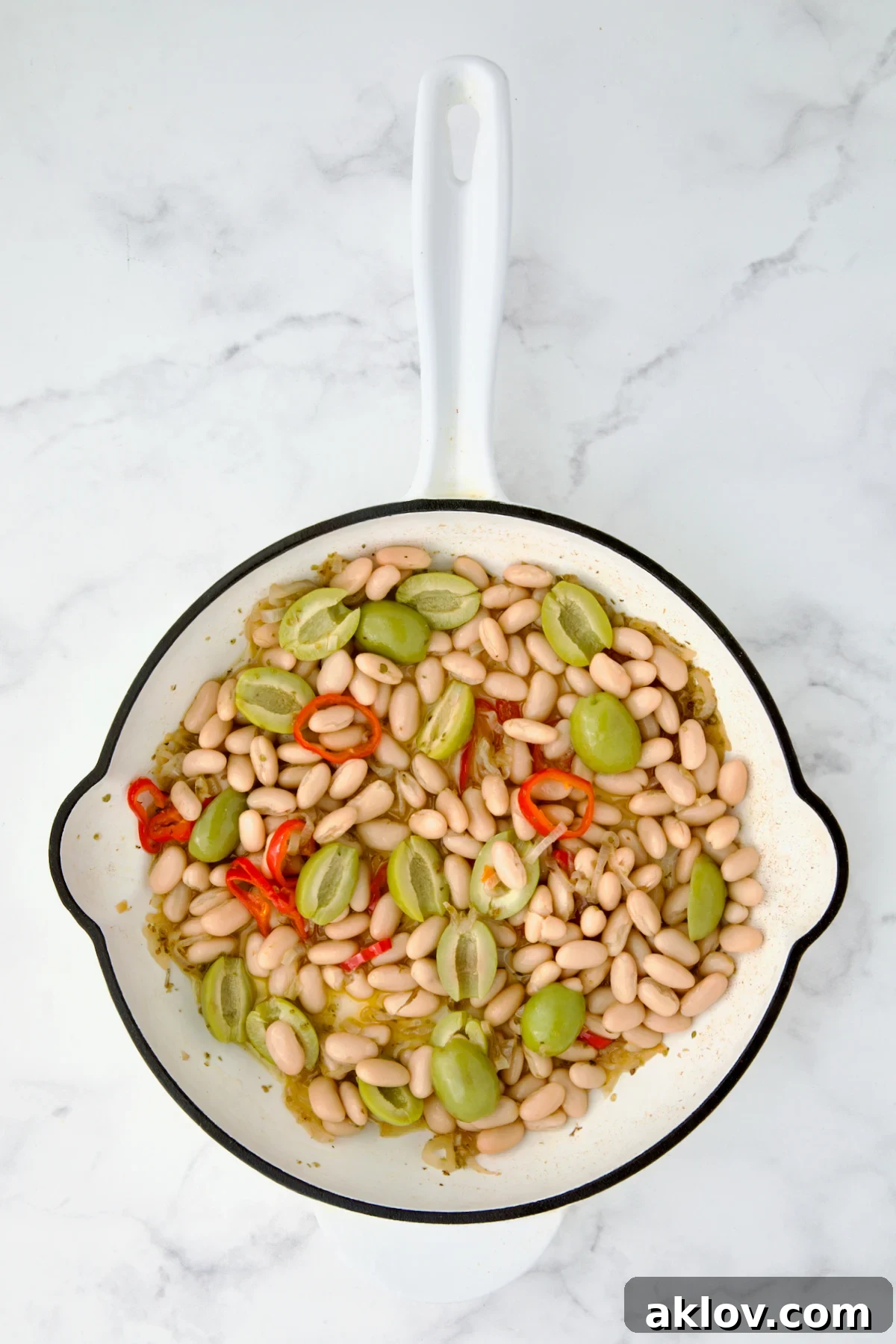 Beans and olives added to wine, oregano, shallot and Fresno chiles in white cast iron skillet.
