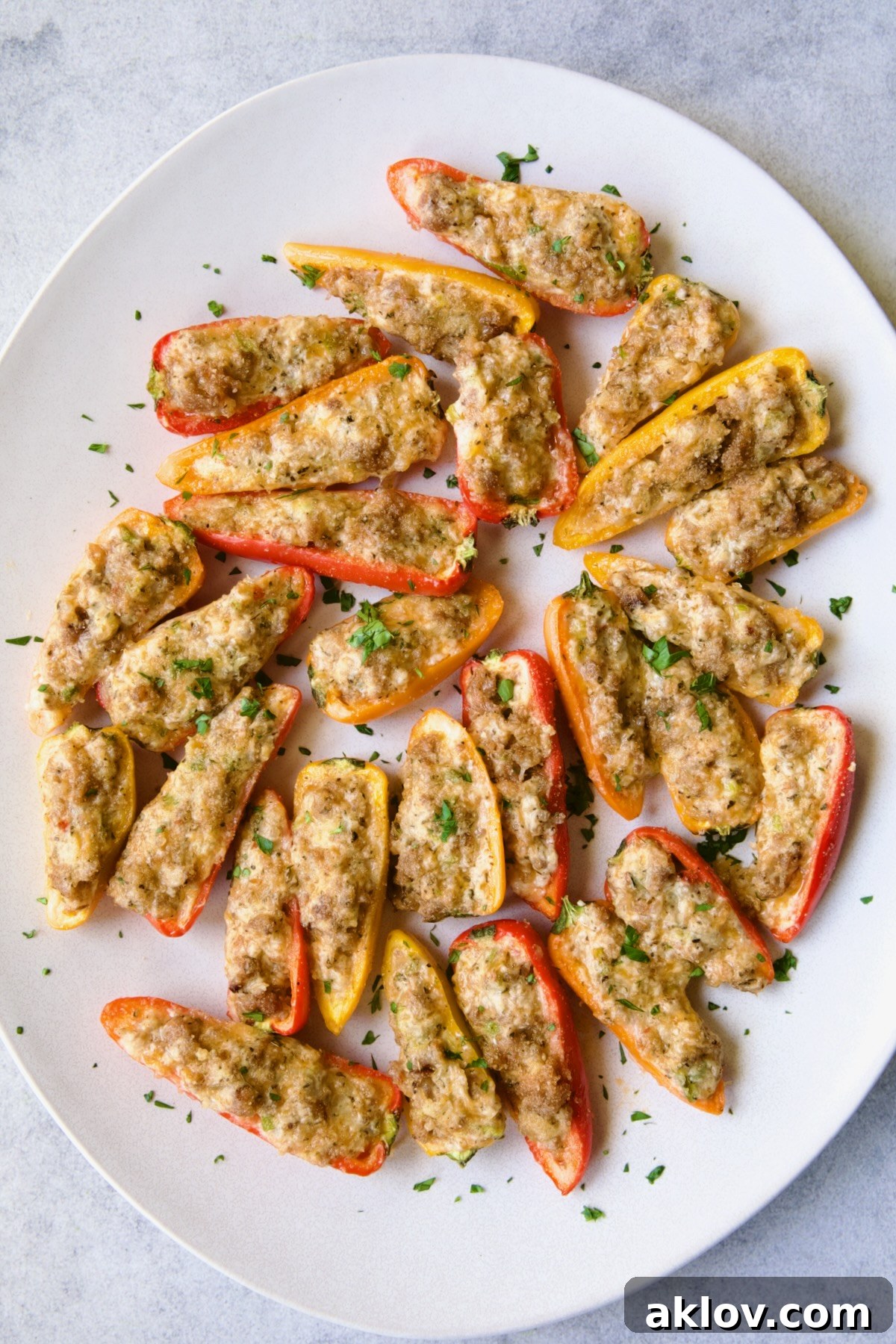 Stuffed Mini Peppers on white oval platter garnished with chopped fresh parsley, ready to be served as an appetizer.