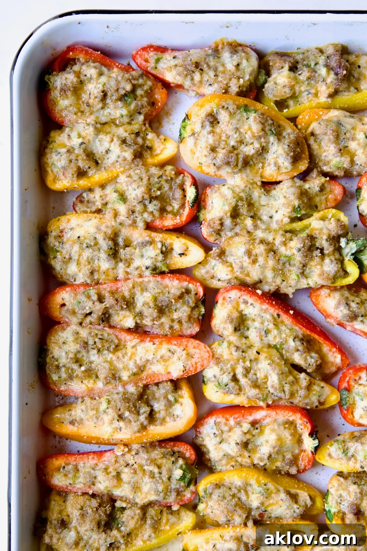 Freshly baked Stuffed Mini Peppers, hot and bubbling, on a white enamel rimmed baking sheet, just out of the oven.