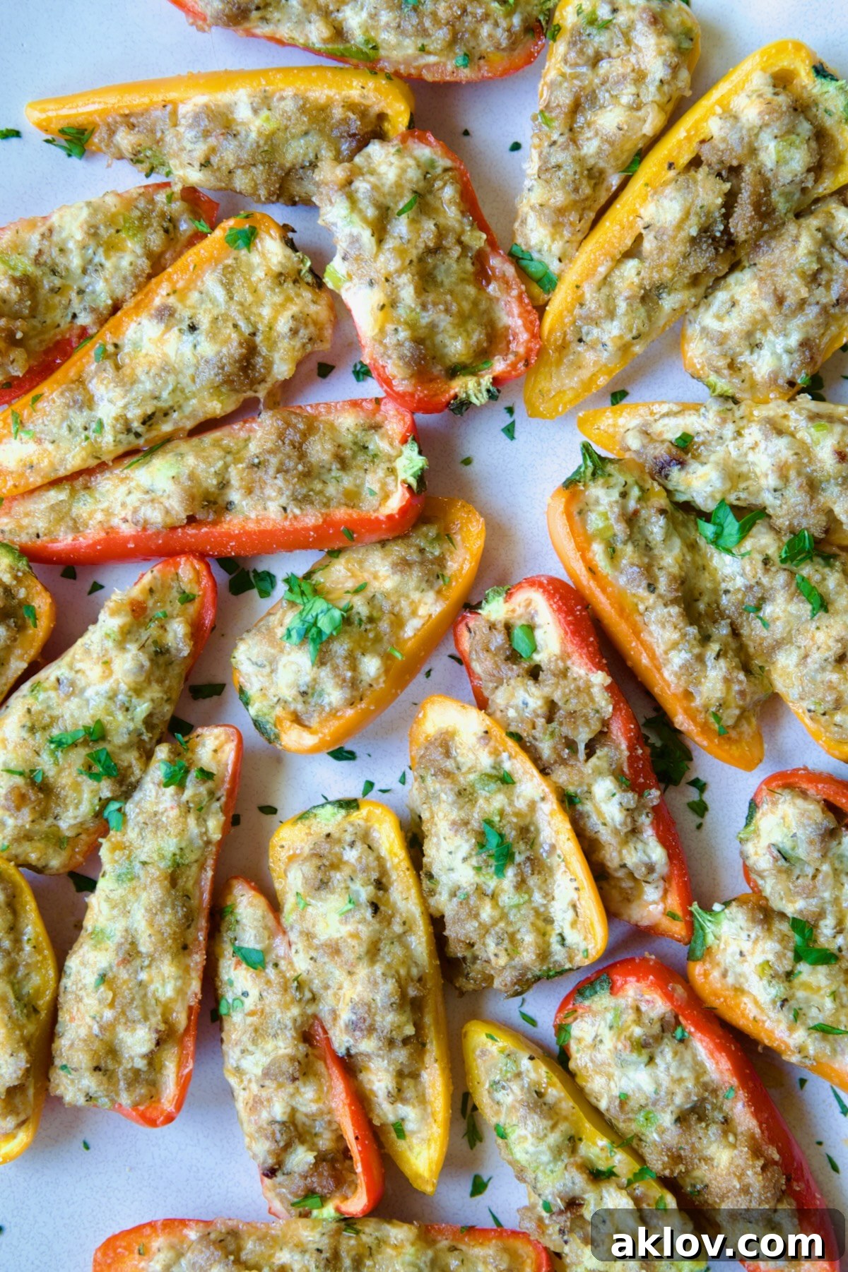 A close-up view of Stuffed Mini Peppers arranged on a white oval platter, garnished with fresh chopped parsley.
