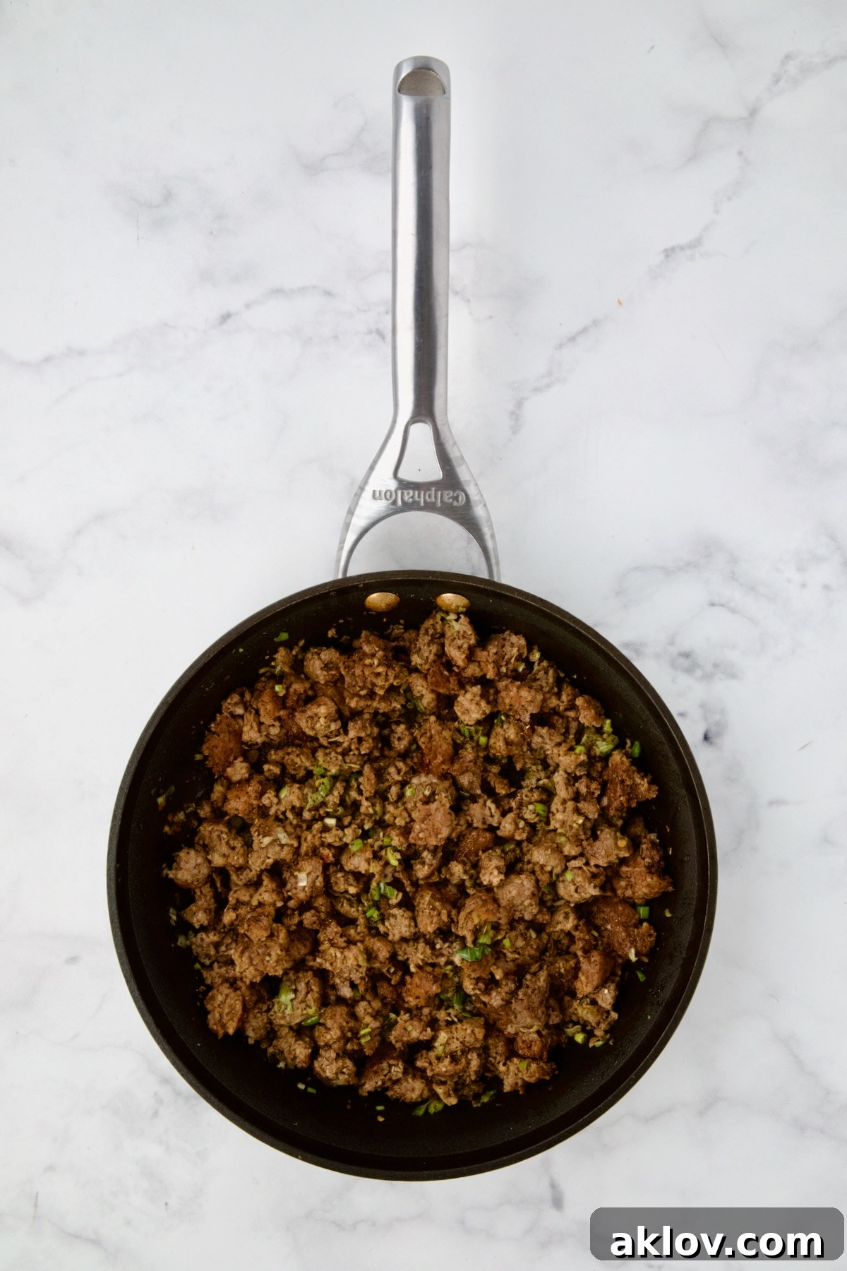 Cooked Italian sausage, chopped scallions, and Italian seasoning mixed in a nonstick skillet.