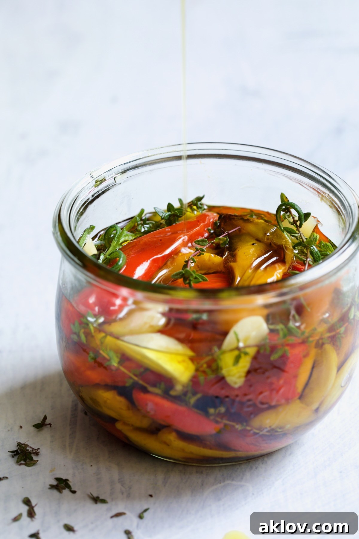 Caramelized Mini Peppers 7 Roasted Mini Peppers in glass jar with fresh herbs and garlic with olive oil being drizzled in.