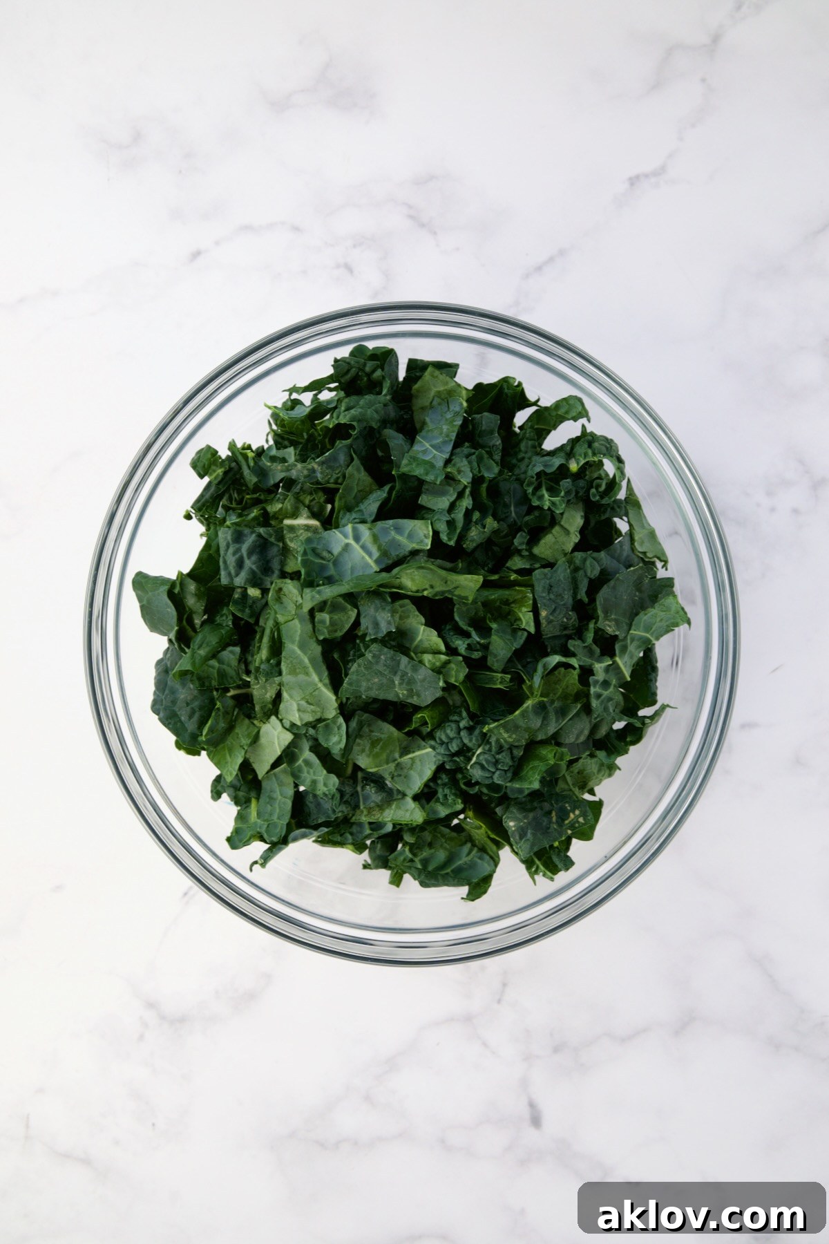Sliced raw Tuscan kale in glass bowl.