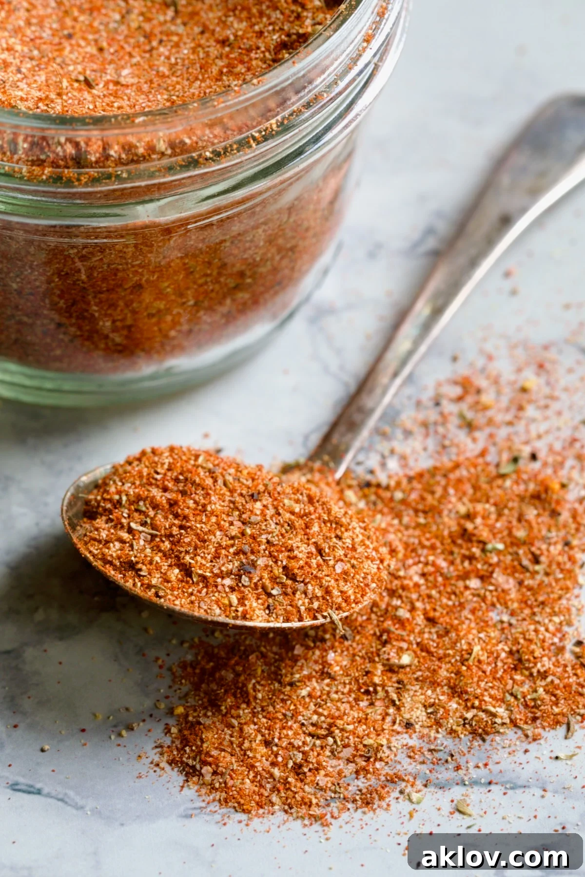 Spoon of Blackening Seasoning spilling over onto surface with jar in the background.