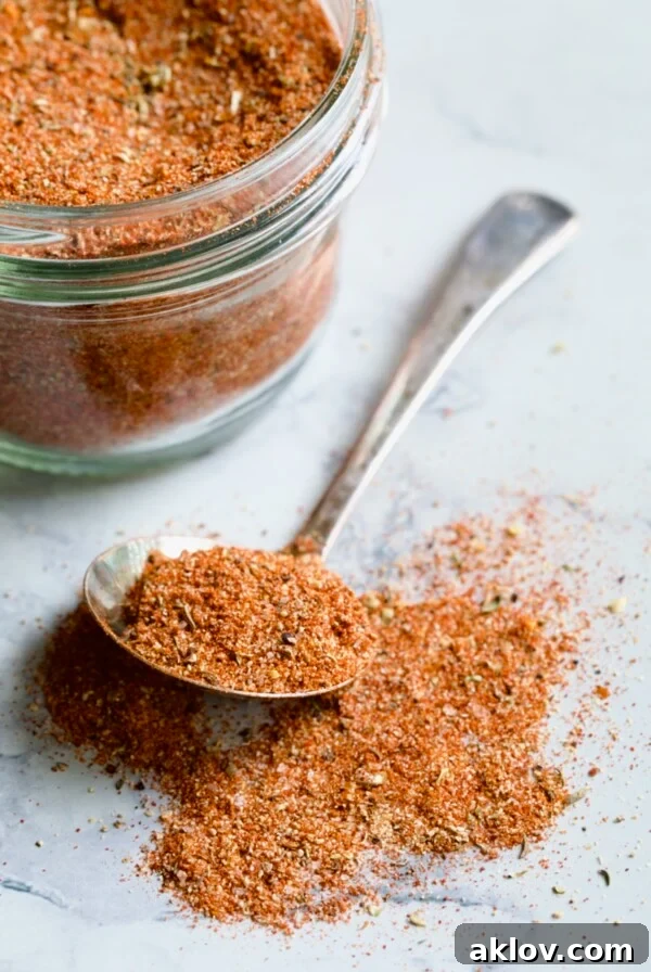 Spoon of Blackening Seasoning spilling over onto surface with jar in the background.