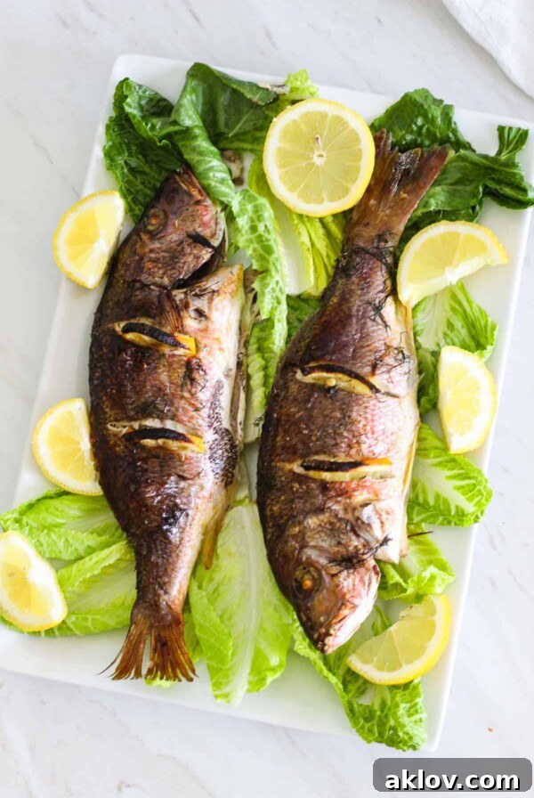 Two baked whole red snapper on a platter, evoking images of a Mediterranean summer by the beach.
