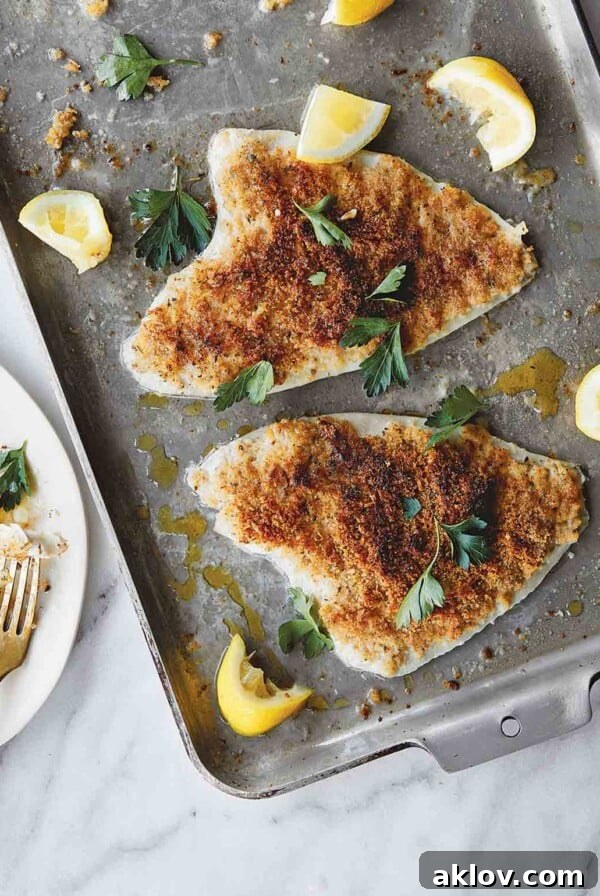Two pieces of delicate Lemon Sole Oreganata baked on a sheet pan, ready to be served.