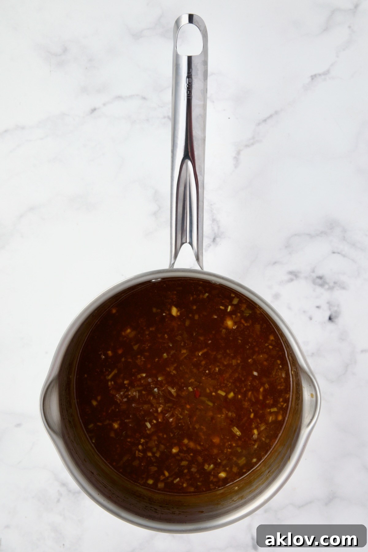 Orange Sesame Sauce ingredients in a stainless steel saucepan, after simmering and thickening to a glossy consistency.