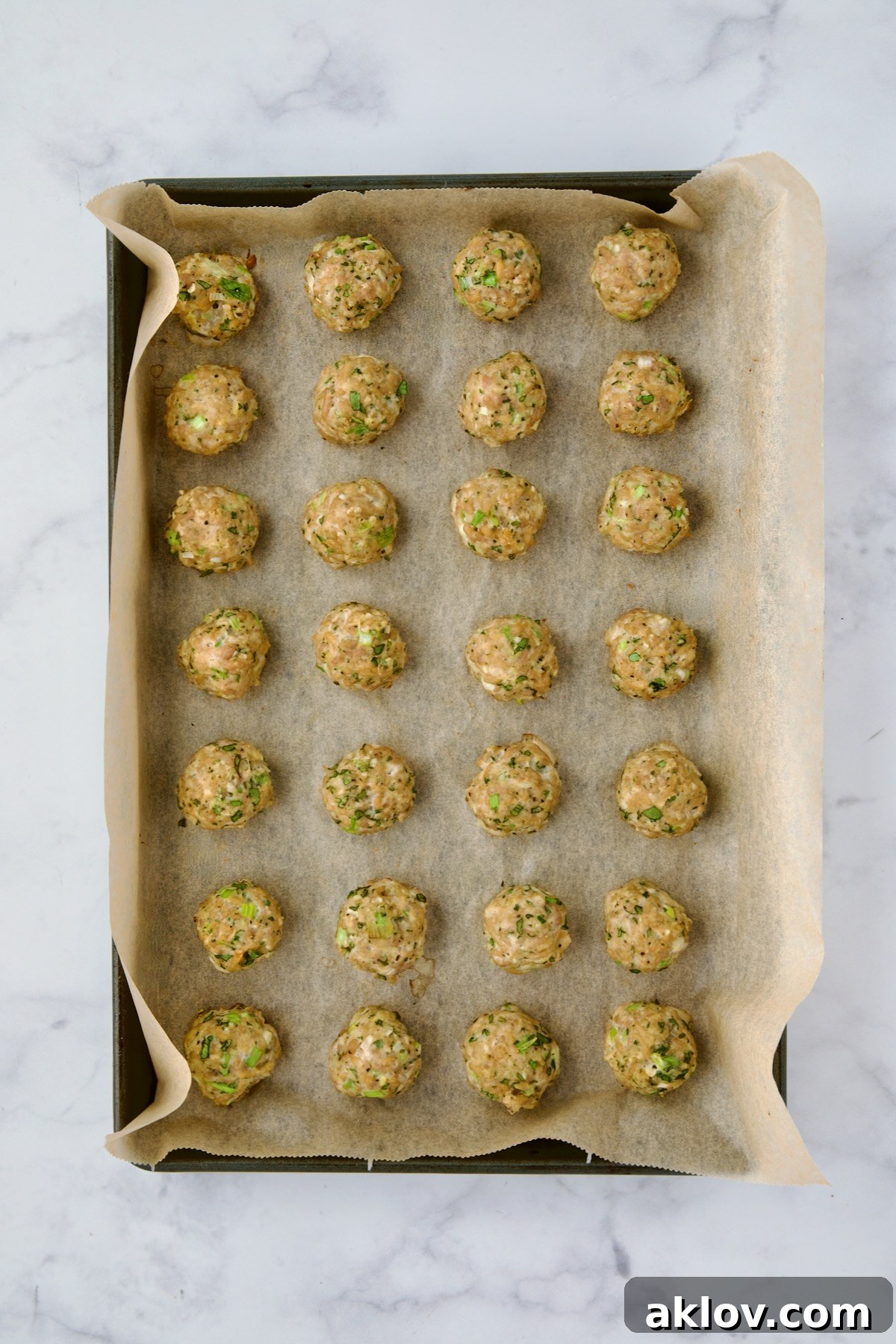 Baked turkey meatballs on a parchment paper-lined baking sheet, golden brown and cooked through.