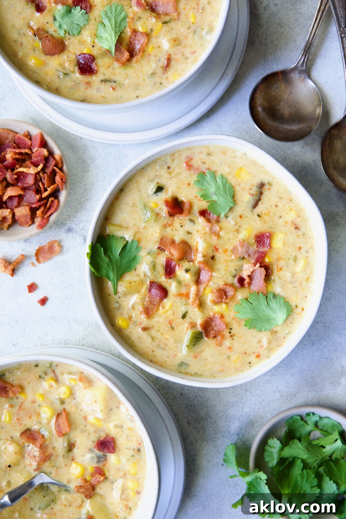 Three perfectly plated bowls of Roasted Poblano Corn Chowder, each garnished with vibrant cilantro, inviting diners to enjoy.